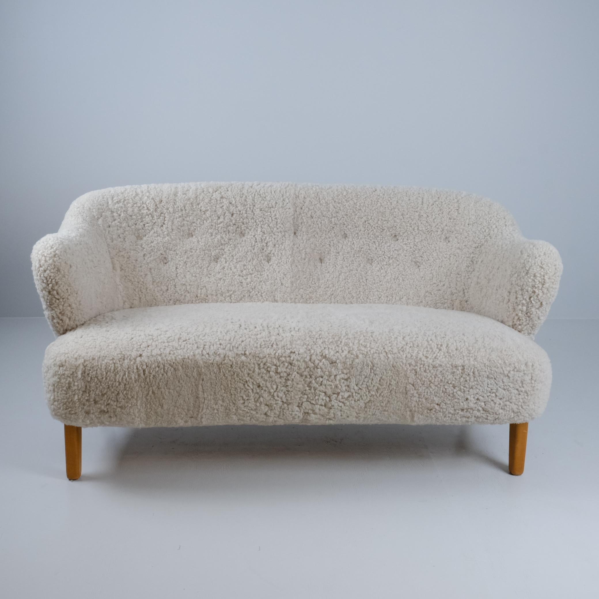 Un precioso sofá de salón del arquitecto danés Flemming Lassen en suave piel de oveja natural beige. El sofá tiene el mismo diseño que la silla Ingeborg de la serie (sofá y silla) que lleva el nombre de la querida madre de Flemming Lassen, la