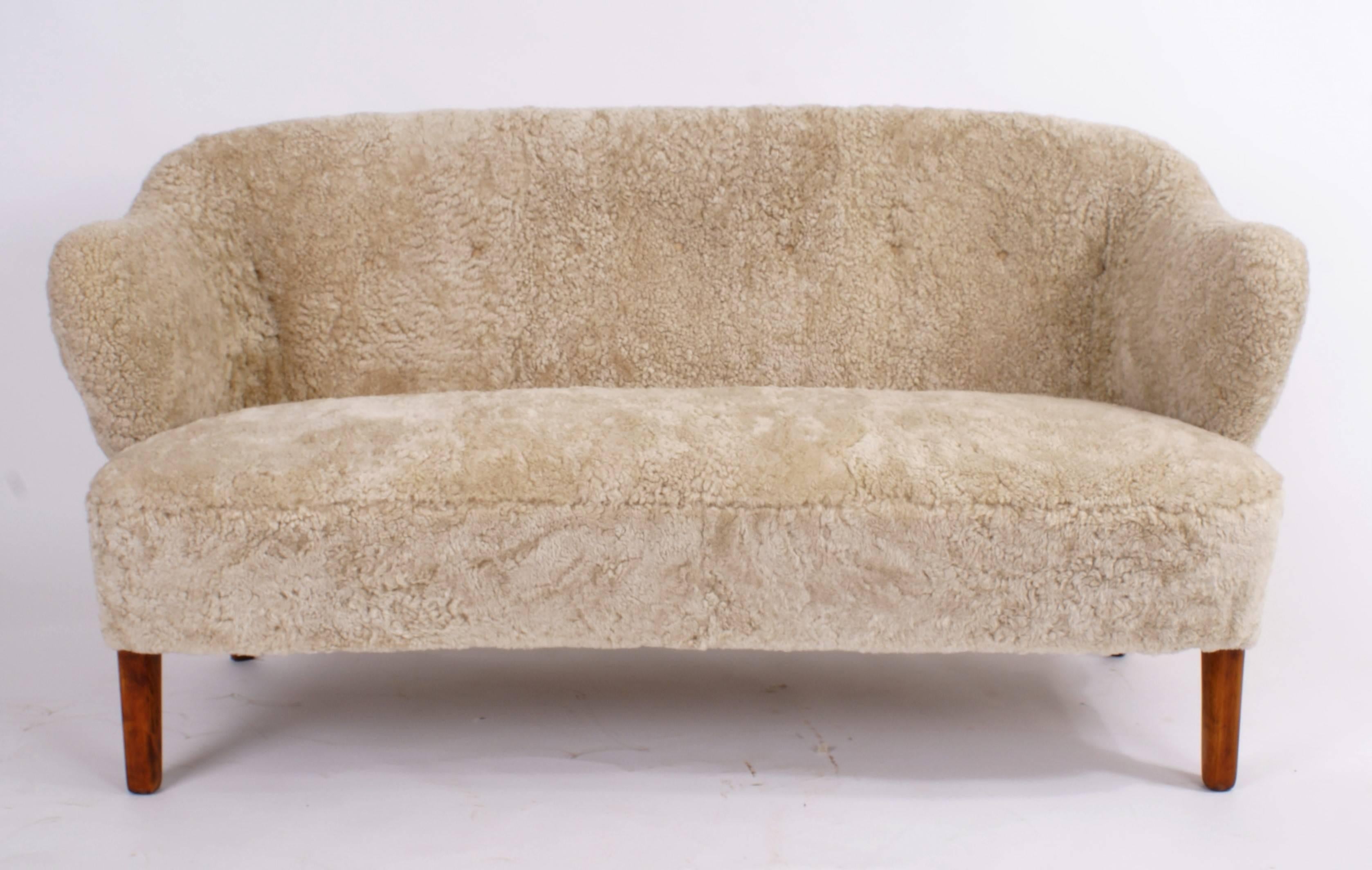 Flemming Lassen, two-seat settee for master cabinetmaker Jacob Kjær, Copenhagen. Beige sheepskin upholstery and ash legs. Designed 1940.

Please view 1stdibs item reference number LU1081215065911 for a pair of Flemming Lassen easy chairs that
