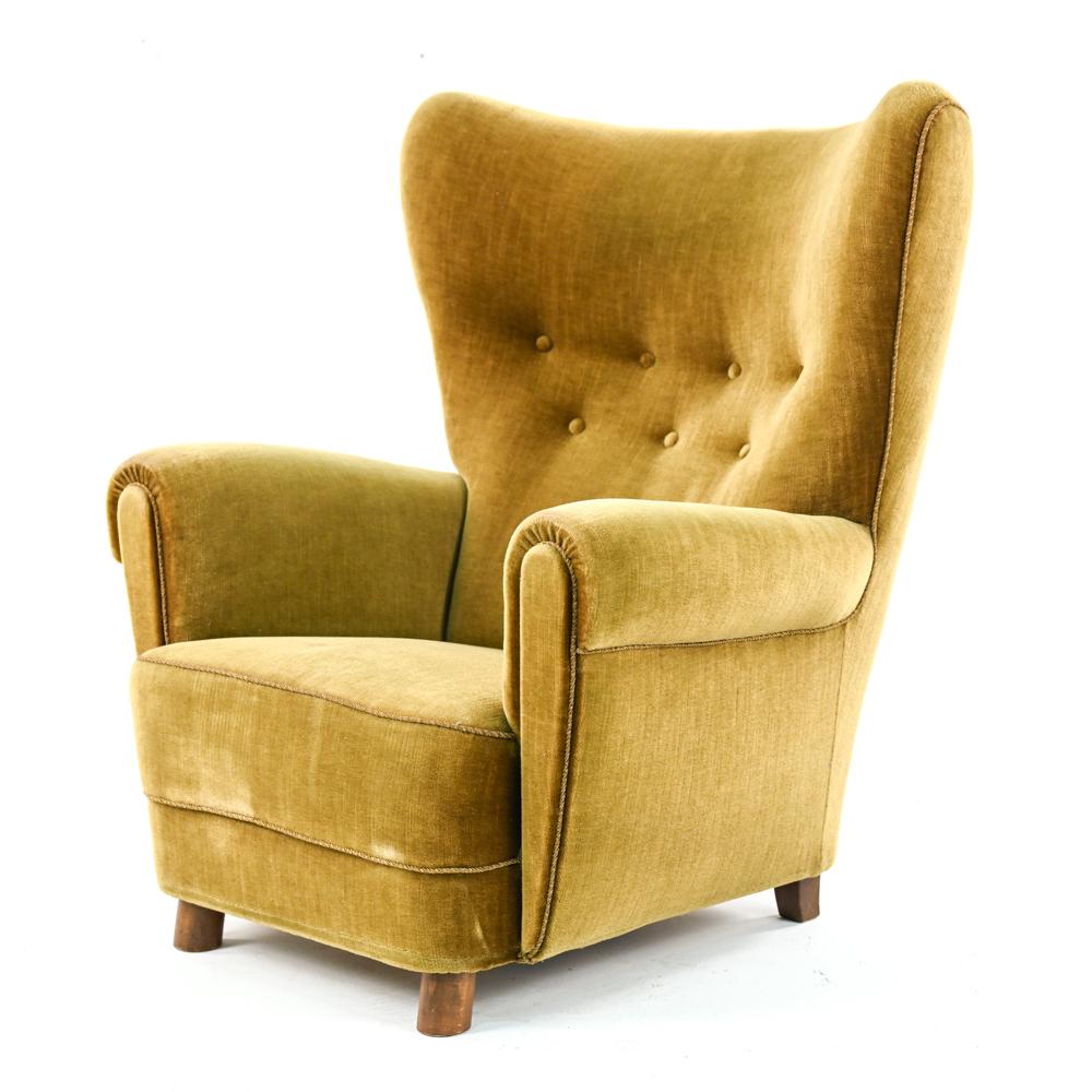 An impressive Danish mid-century wingback lounge chair in the manner of Flemming Lassen. With tufted backrest. c. 1940's.
