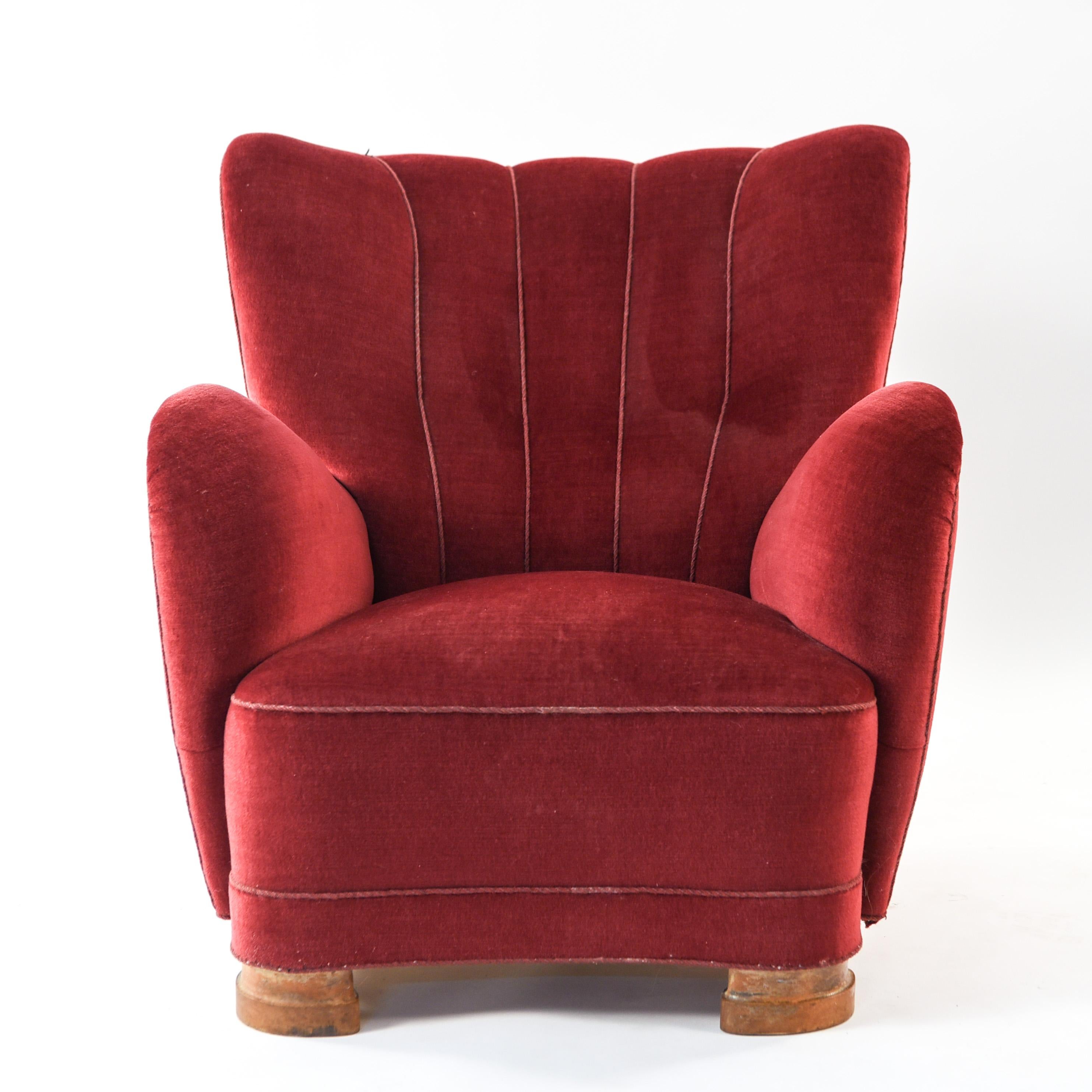 This Danish midcentury wingback lounge chair is in the manner of Flemming Lassen. This chair is upholstered in a pinkish mohair and features a scalloped back detail.