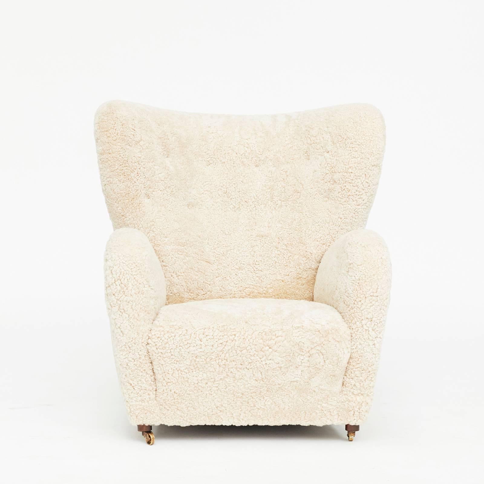 Flemming Lassen style Easychair. Freestanding. Upholstered with white sheepskin. Front legs with wheels. Manufactured in Denmark, circa 1940.