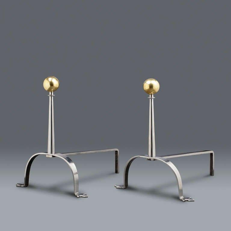 Brass and polished steel andirons with tapering rounded collared columns capped with large brass balls on hooped splayed feet.
   