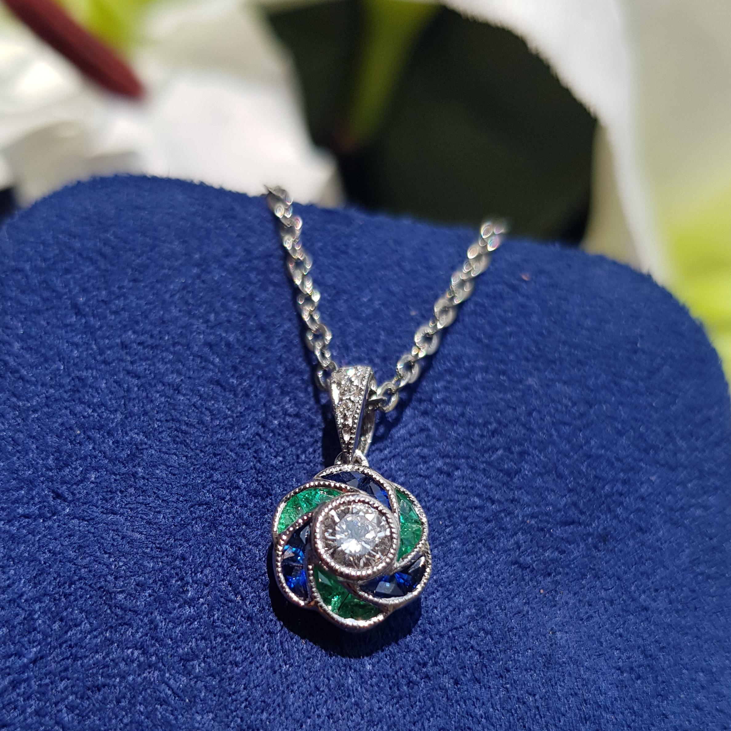 Perfect with everyday wear, this charming vintage Art Deco revivalist design pendant features brilliant-cut diamonds surrounded by emerald and bright blue sapphire for rose petals finished look all in 18K white gold.

Information
Style: