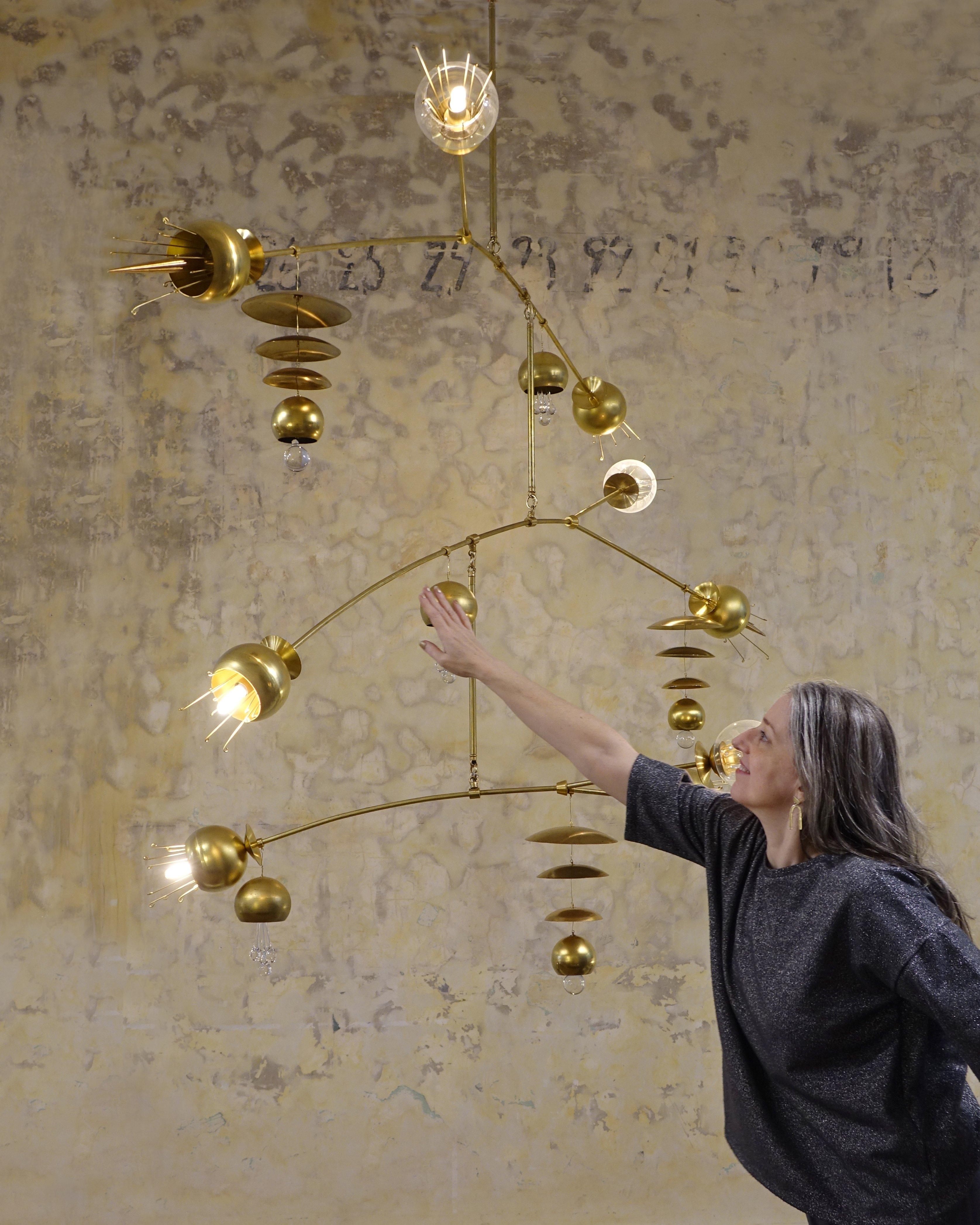 The Fleurish chandelier is a modern, organic mobile-style lighting fixture designed by Michele Varian and built in our NYC studio. It is solid brass construction with glass and crystal accents, mimicking flora from Japanese imagery. The fixture is
