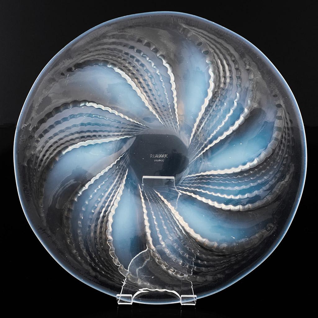 Fleurons, an Art Deco plate by René Lalique (1860-1945). Opalescent and clear glass with geometric motif of radiating, stylised leaves.

Stencil etched R Lalique France to centre.

René Jules Lalique (French, 1860–1945) was a renowned jeweller and