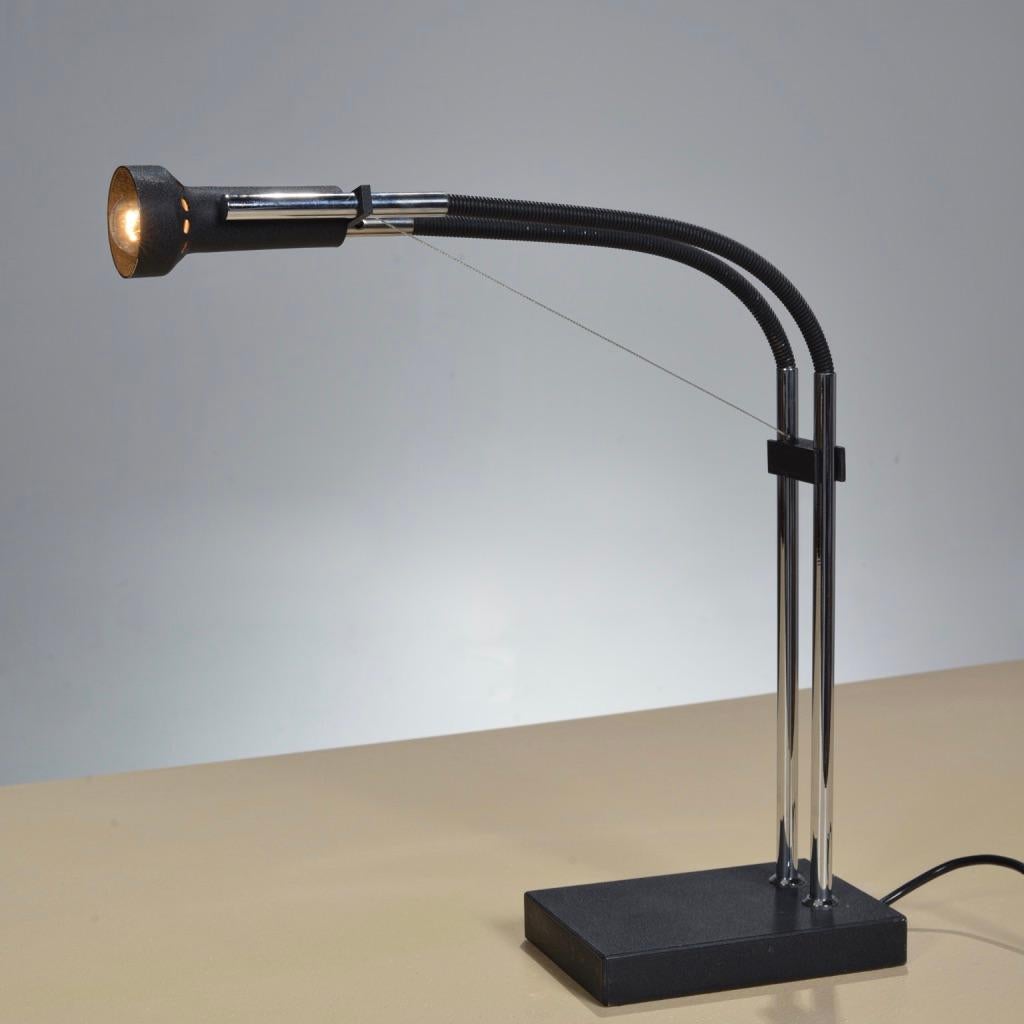 Lampe de table Flexa conçue par Angelo Lelii pour Arredoluce, vers 1975. 
L'ampoule est enfermée dans un abat-jour en métal émaillé et flanquée de deux colonnes chromées parallèles.
 Cette lampe comporte un contrepoids rectangulaire entre les