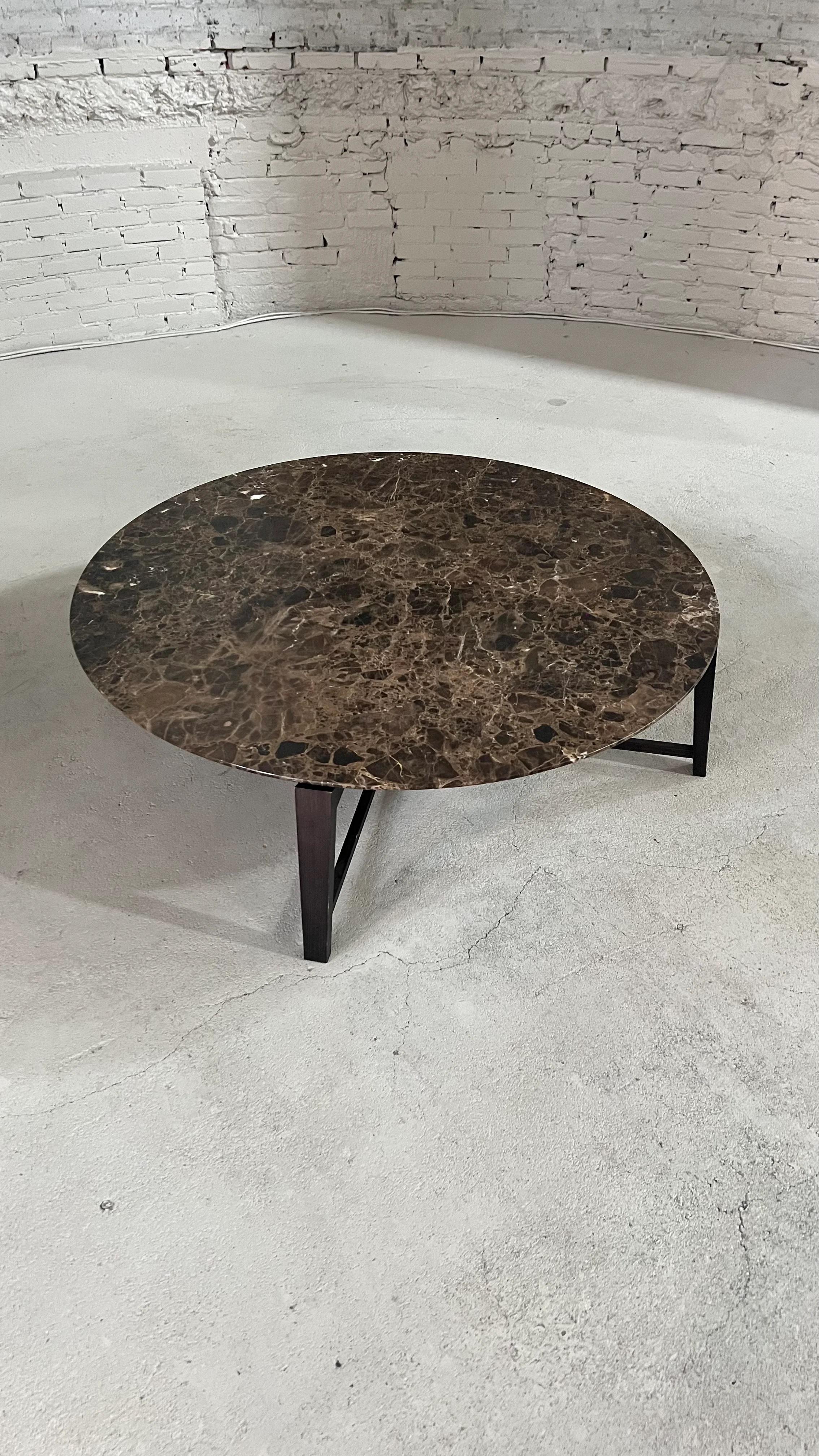 Coffee table with beveled edge made in emperador marble. The base is in solid wood, with crossbars that connect the four legs, forming a particular crossed design near the floor.

The coffeetable is made & designed by Flexform in Italy.