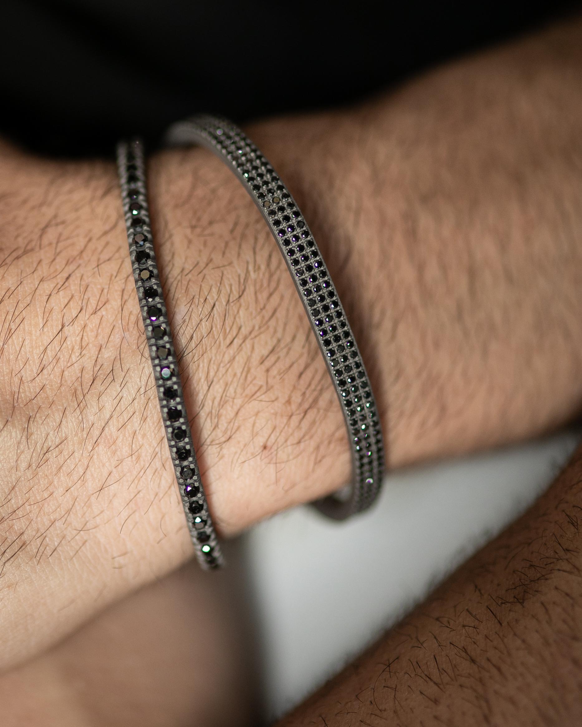Le bracelet souple en titane est issu de notre collection Hommes. Le bracelet est orné de 58 magnifiques diamants noirs naturels d'un total de 3,36 carats et de détails en or rose 18 carats. Le diamètre du bracelet est de 6,5 cm. Parfait pour tous