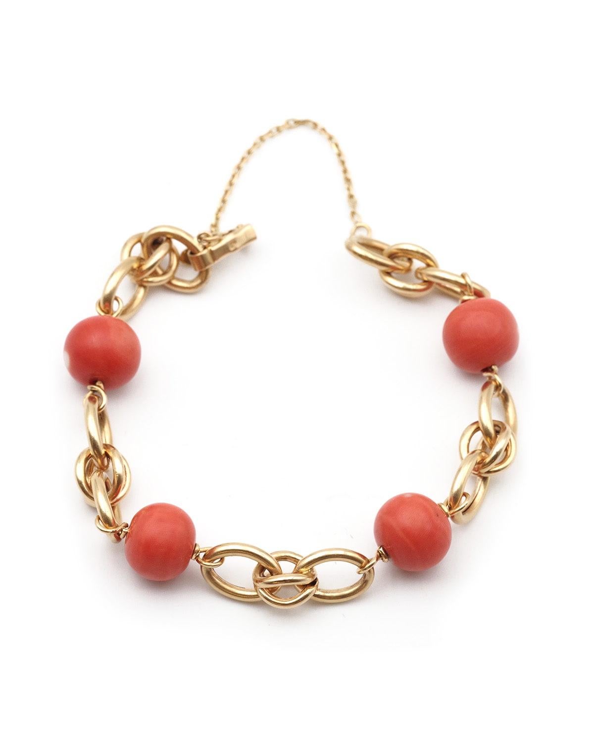 Flexibles Korallenperlenarmband aus 18 Karat Gelbgold. Armband aus vier Korallenperlen, die sich mit einem einfachen und einem doppelten ovalen Glied abwechseln, der Verschluss ist durch eine Kette gesichert. Die Korallenperlen haben natürliche