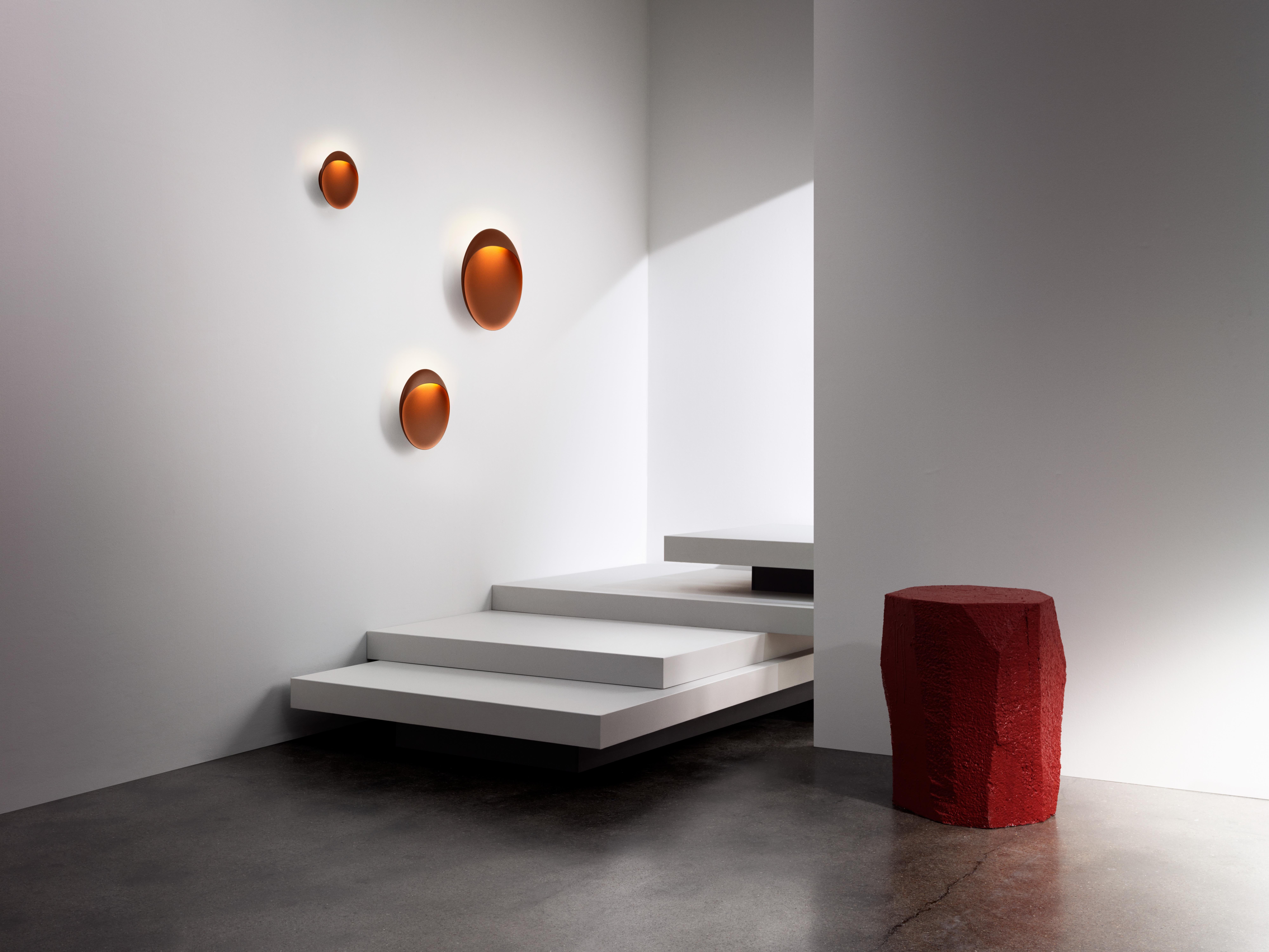 Large 'Flindt' indoor/outdoor wall light in Cortens Red for Louis Poulsen. A circular, wall-mounted fixture that brings bold, sculptural illumination to both indoor and outdoor spaces. The slim, elliptical lamp has a floating appearance that, paired