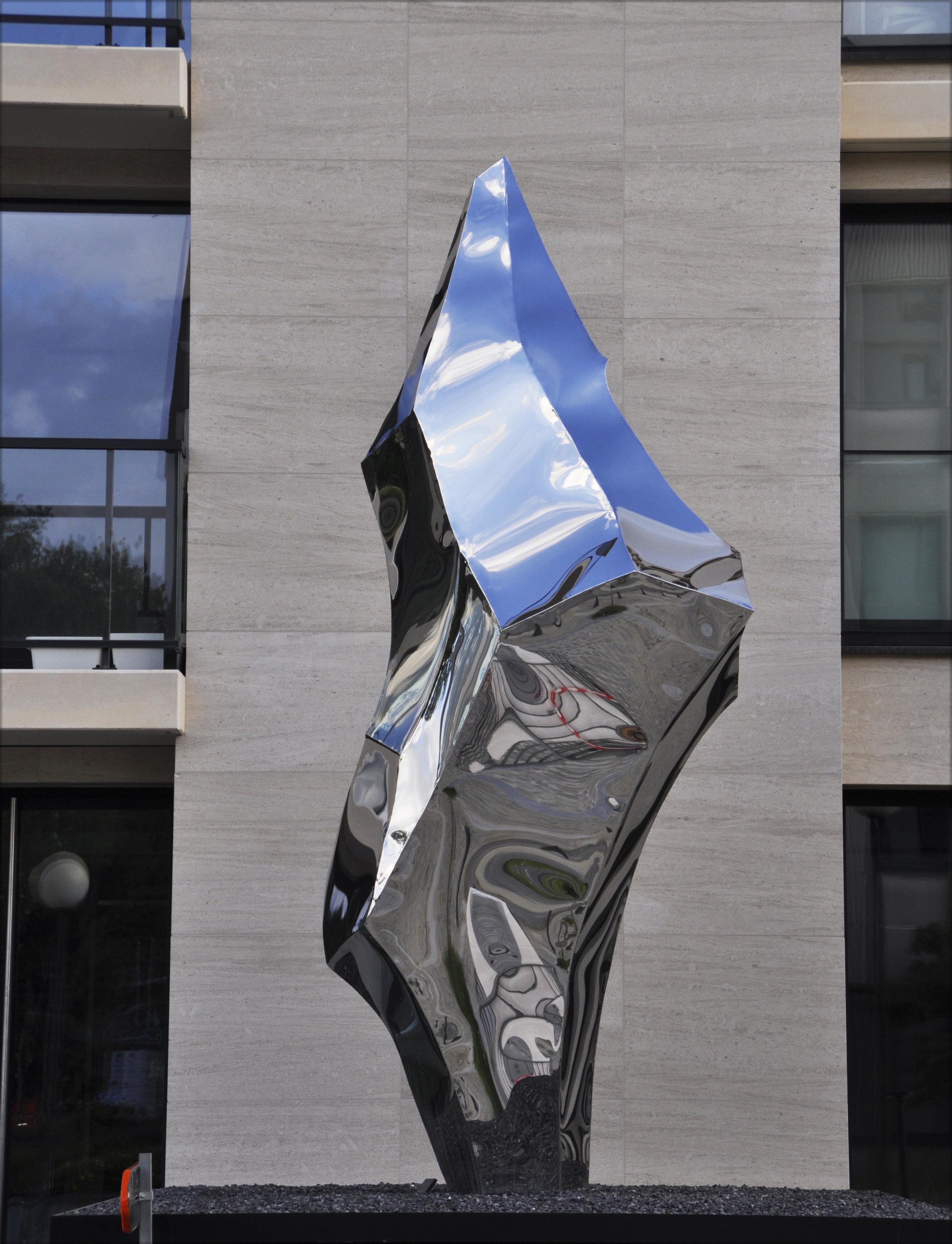 Scultura Flint II di Pol Quadens 
Un pezzo unico.
Dimensioni: D 90 x L 140 x H 450 cm.
Materiali: Acciaio inossidabile lucidato.

Pol Quadens è nato a Bruxelles. Suo padre era attivo nel campo dei compositi e dell'industria metallurgica e il mondo