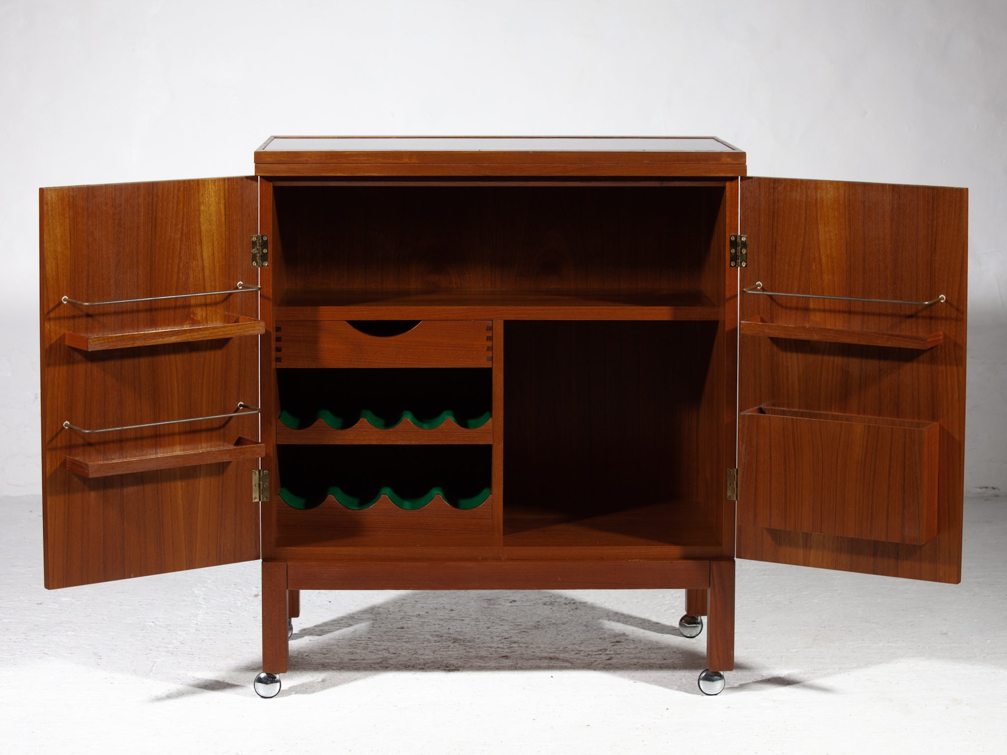 Mid-Century Modern “flip top”, bar cabinet/ cart by Torbjorn Afdal for Mellemstrands Møbelfabrik / Bruksbo of Norway, circa 1960s. 
Featuring in teak, with a fully finished back and teak interior. The finished back side makes this cart ideal for