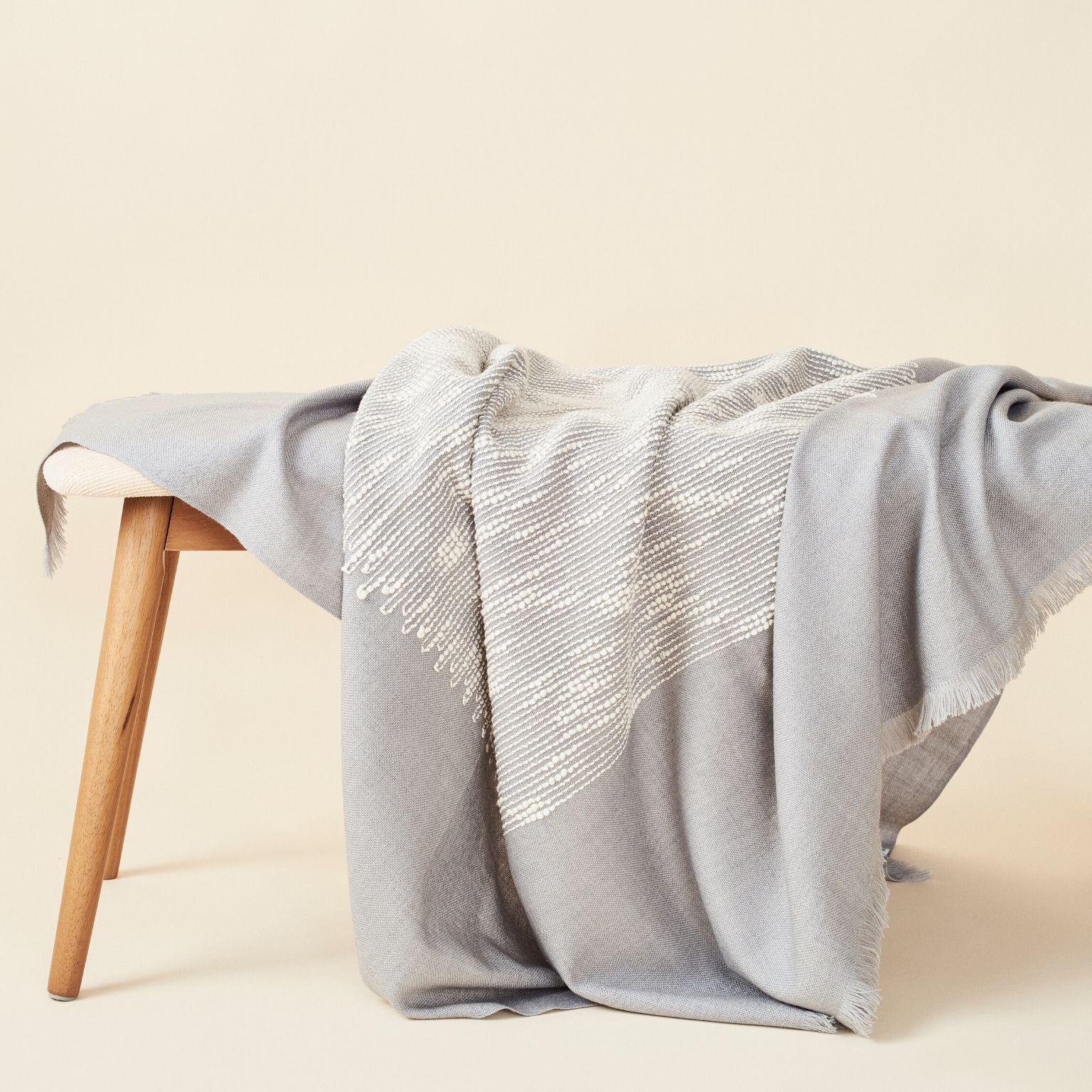 Custom design by Studio Variously, FLO grey throw / blanket is a beautifully handwoven and carefully hand embroidered piece by master weavers in Nepal , and dyed entirely with earth-friendly certified Swiss dyes. A sustainable design brand based out