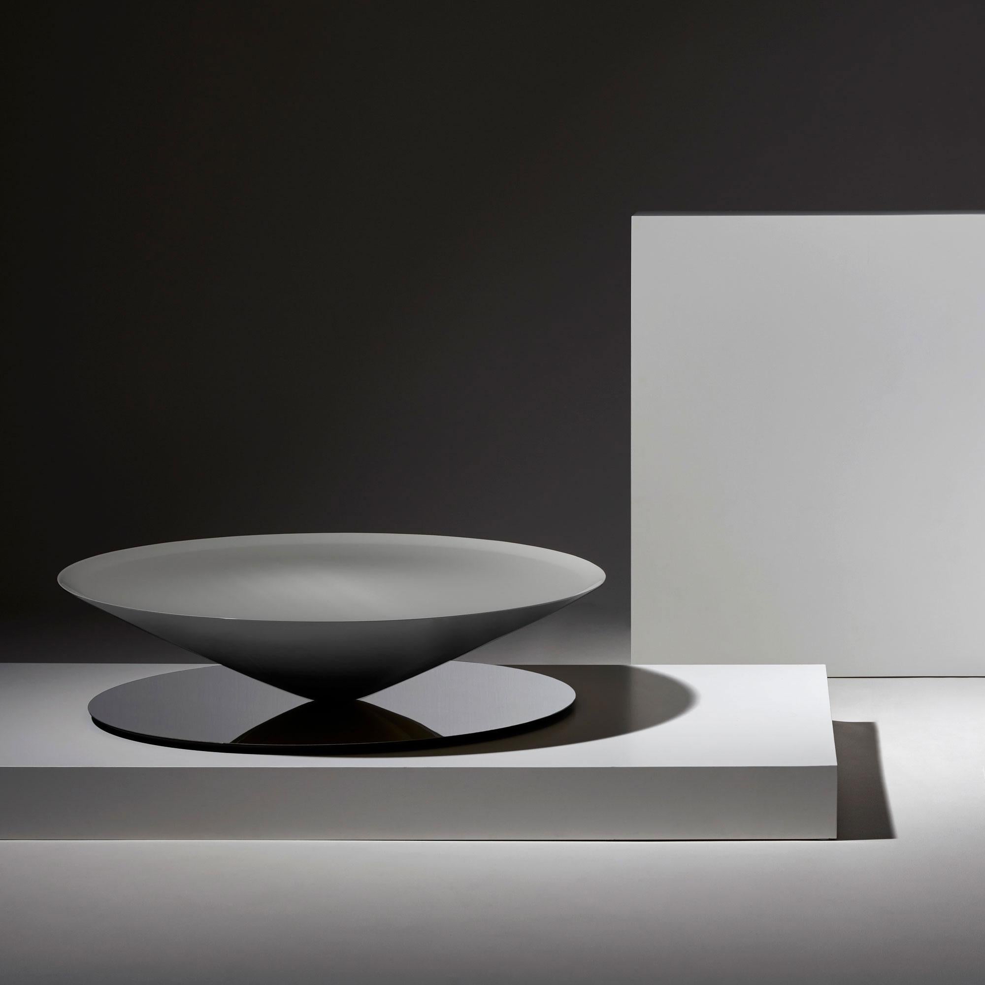 Float is a sculptural coffee table that challenges senses and perception. A massive metal cone apparently floats above a mirror polished steel base.
The geometrical design is softened by refined details such as the bezelled lip on the edges of the