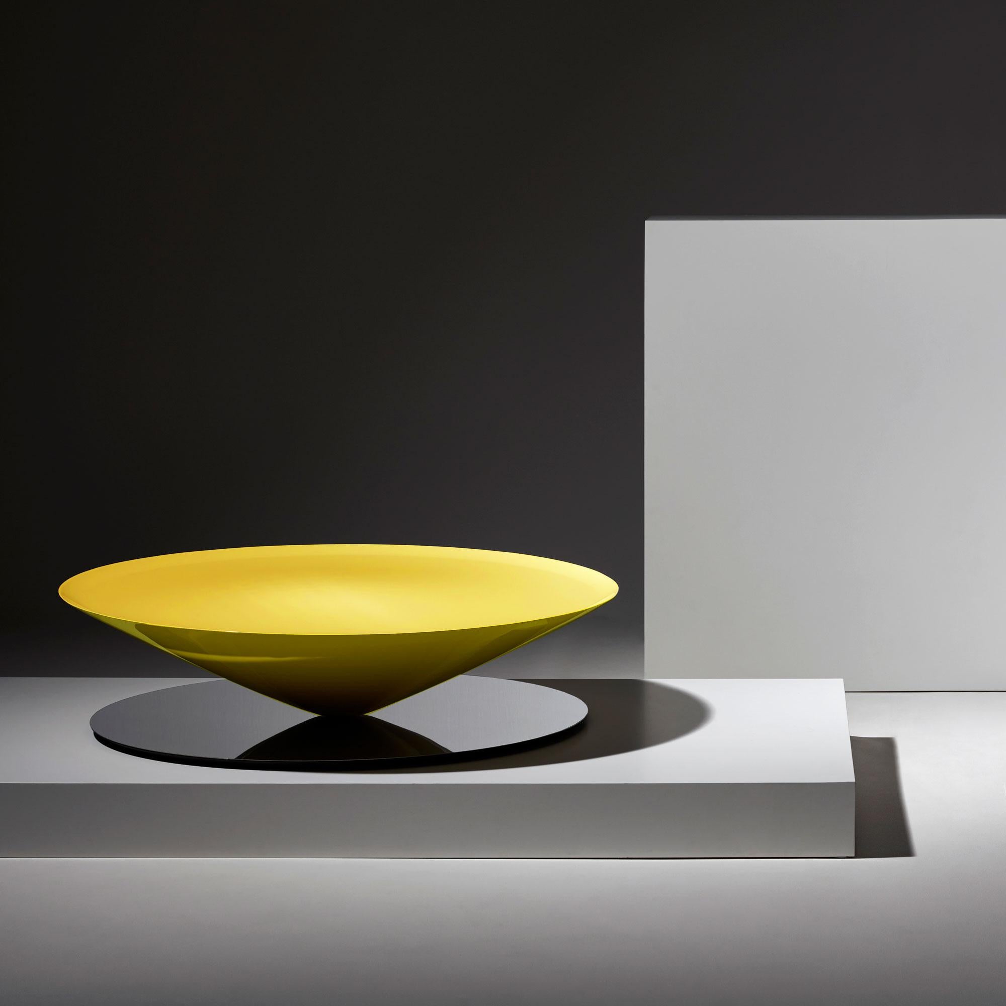 Float est une table basse sculpturale qui défie les sens et la perception. Un cône massif en métal flotte apparemment au-dessus d'une base en acier poli miroir.
Le dessin géométrique est adouci par des détails raffinés tels que la lèvre biseautée