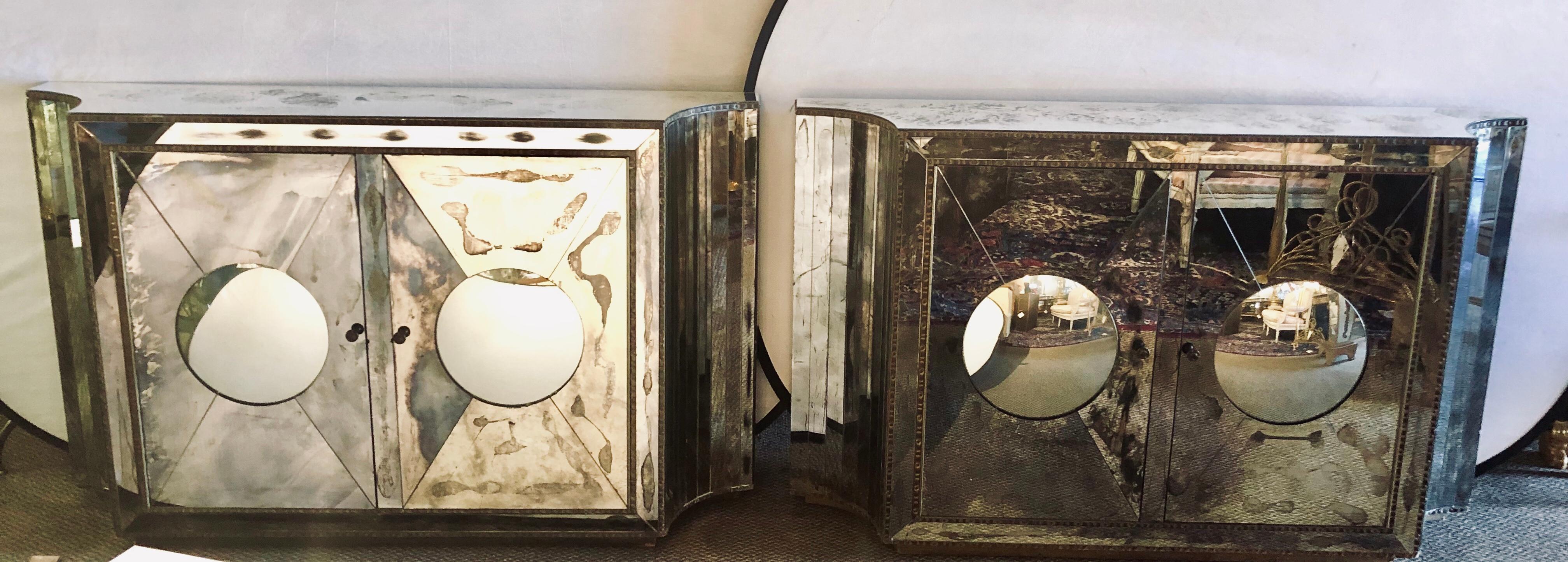 Pair of stunning one of a kind Art Deco rare concave sided with circular convex front double door all mirrored cabinets or console tables. The pair appear to be floating on air as they stand on distressed wooden carved hidden bases. Each having a
