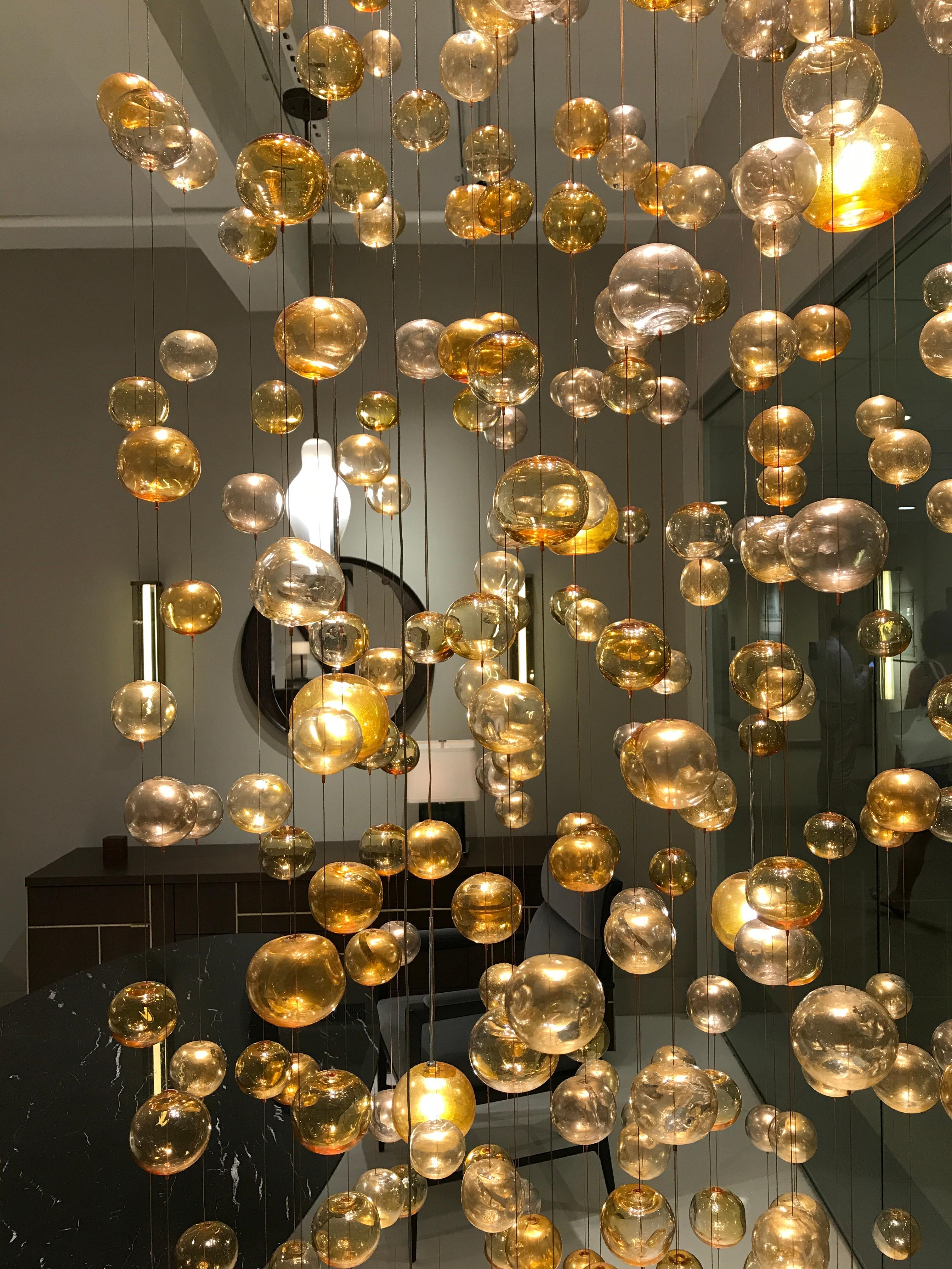 Chandelier with 52 strands of 780 bubbles suspended from an LED illuminated canopy. Delicate in appearance, yet substantial, the optically rich glass bubbles are handblown and dented for maximum light reflection. Measures: Canopy has 40