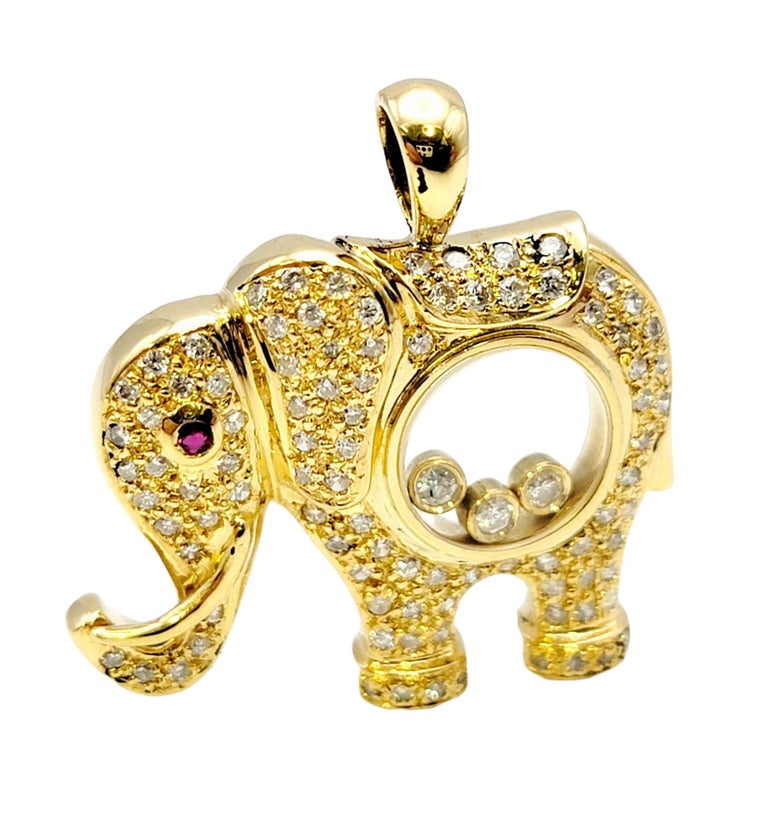 Glittering pave diamond elephant pendant with a playful floating diamond center. This unique piece features an  18 karat yellow gold elephant embellished with glittering pave diamonds. The eye of the creature is a single bezel set ruby. At the