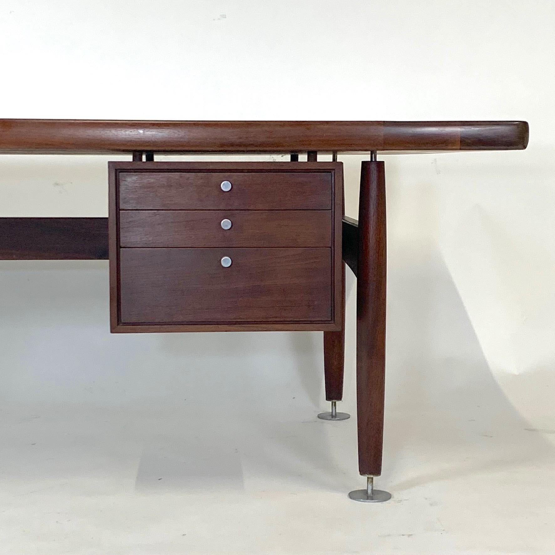 A sleek leather topped walnut desk with a bank of drawers and machined pulls and oversized decorative glides by Lehigh Furniture attributed to Ward Bennett. Very impressive desk with some wear and patina to the leather but shows very well. Wood is