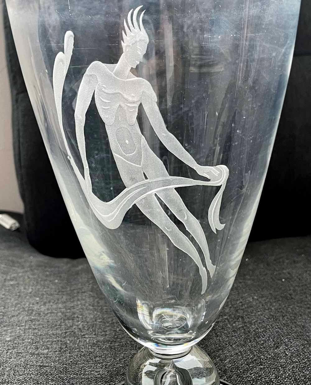 Large, rare and impressive, this sandblasted glass vase by Franz Grosz depicts a nude male figure floating in the air -- perhaps a dancer in the midst of a leap from the stage floor -- holding a length of drapery that is fluttering in the breeze.