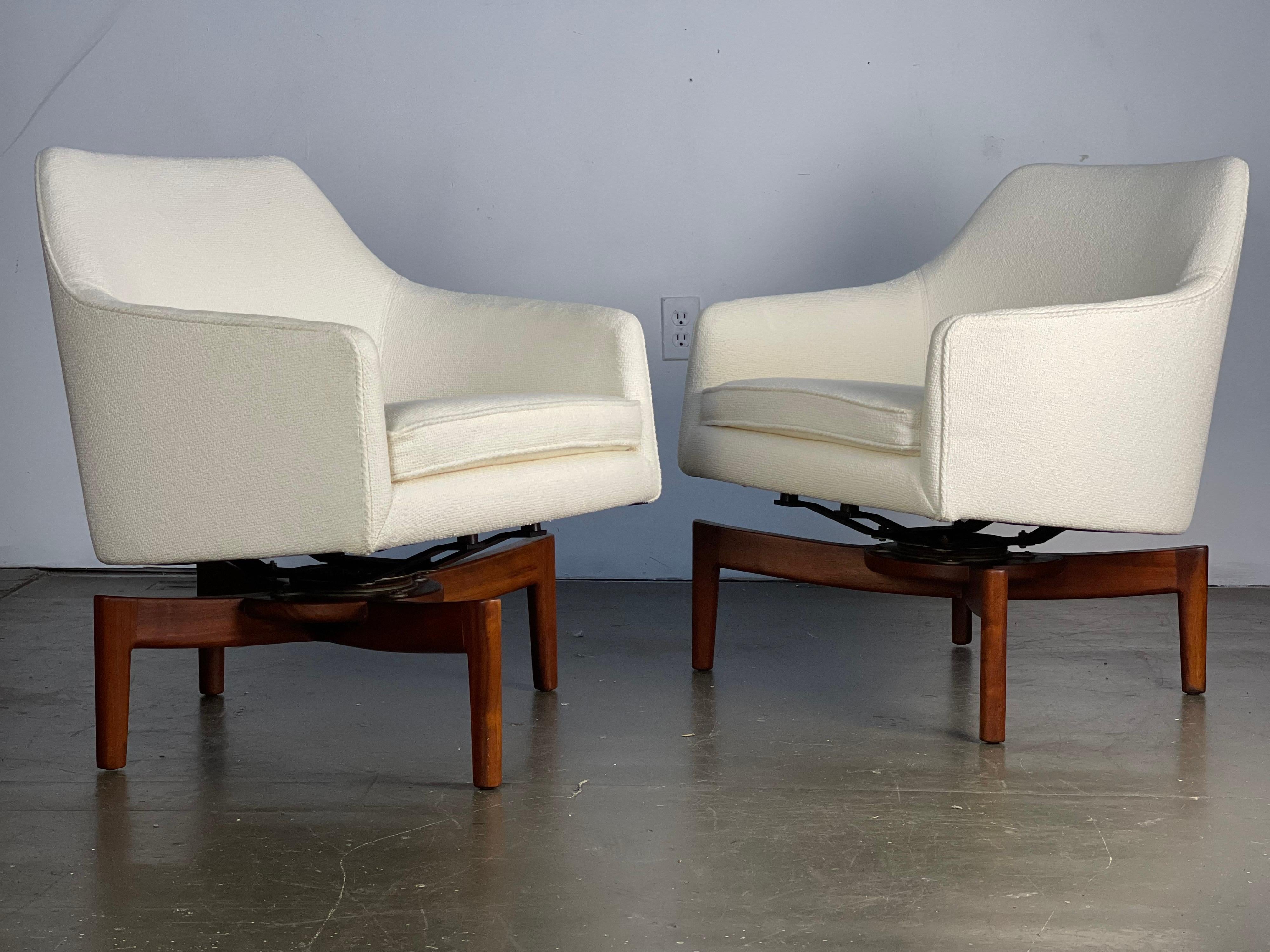 Incredible pair of floating swivel lounge chairs by Jens Risom that are pitched up with the unique exoskeleton walnut legs that are wide and taller in the front for the wide seat of the chair and more narrow in the back giving the sleek appearance