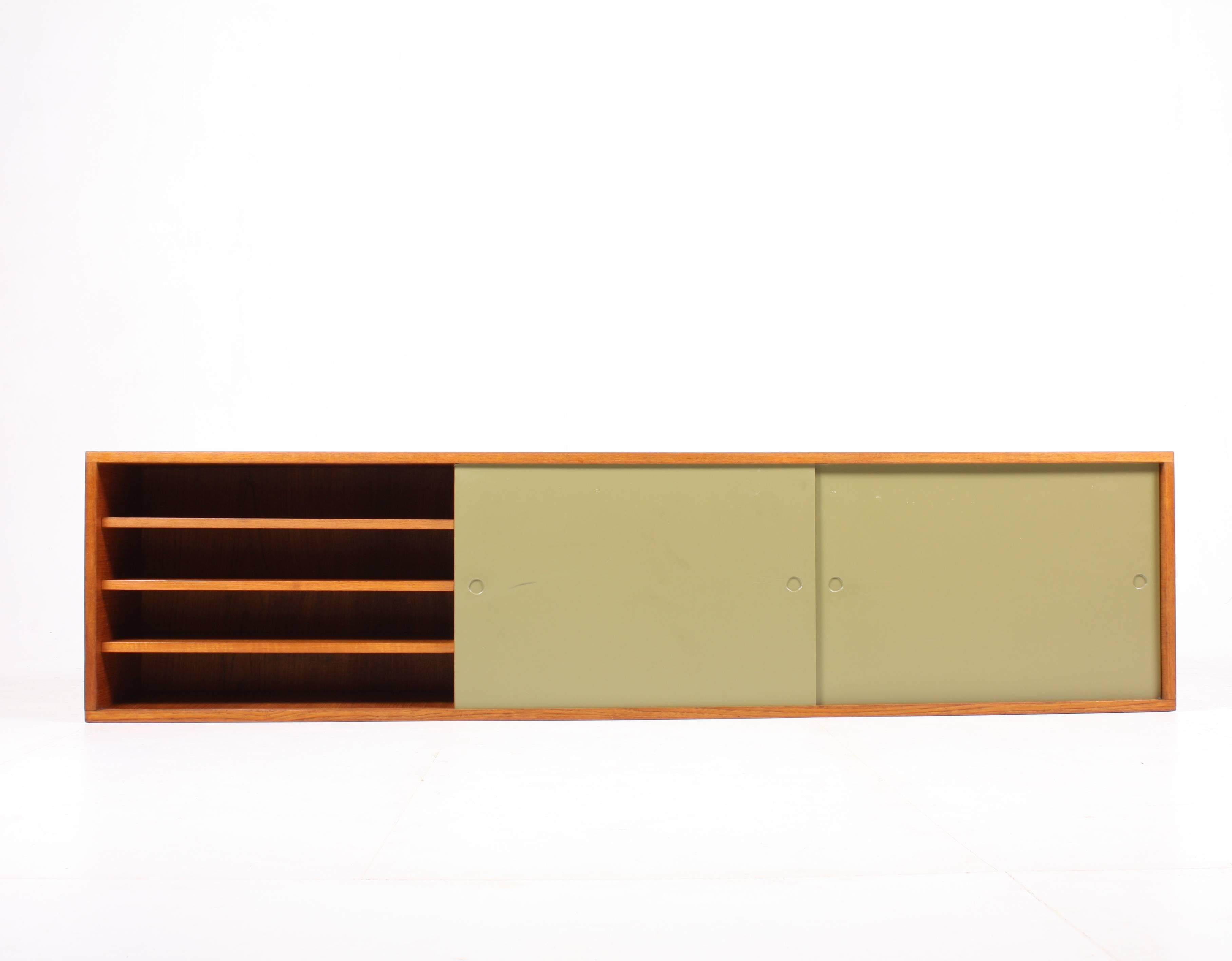 Wall-mounted sideboard in teak with lacquered panels in moss green. Designed and made by Heinrich Roepstorff design studio Denmark in the 1950s. Great original condition.