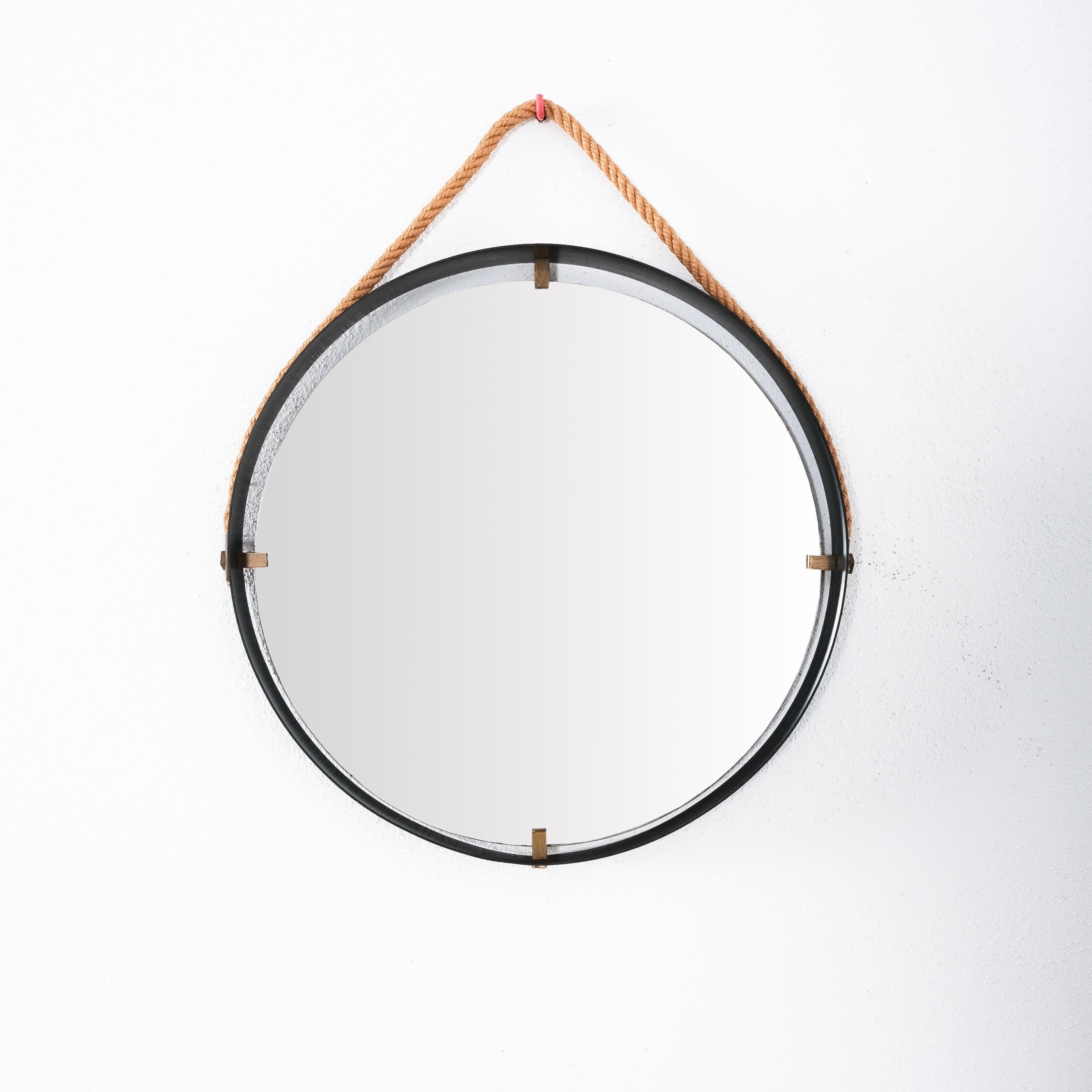 Floating iron frame mirror, Italy, circa 1955

Mid century Italian iron frame mirror with a cord suspension and brass details. 
It’s in great condition, the mirror glass shows minimal staining.
Dimensions are: 18.9