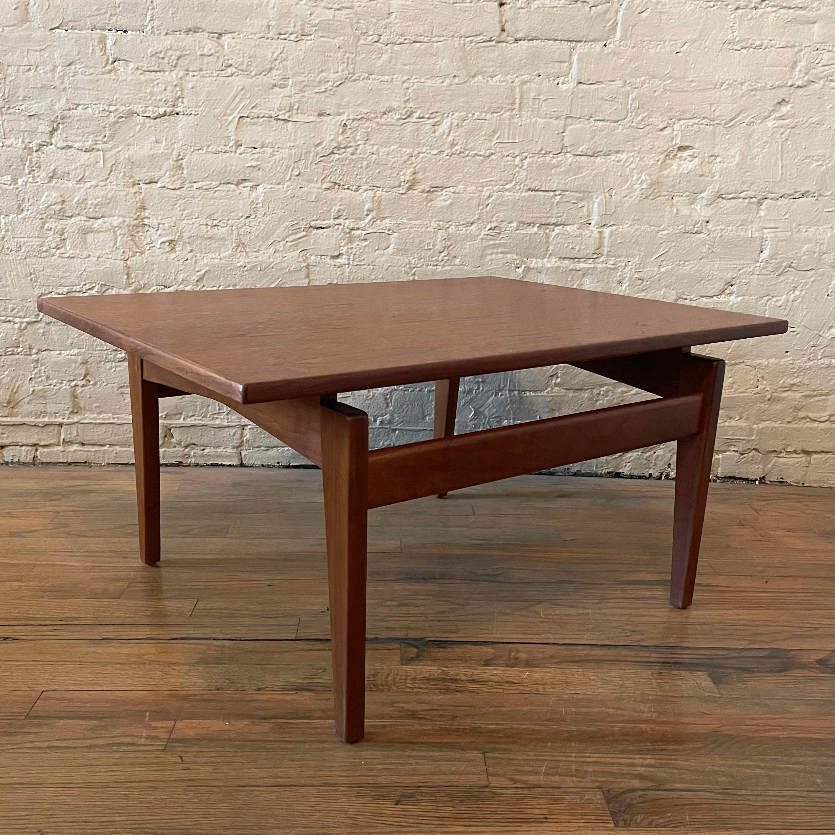 Mid-Century Modern, angular, walnut coffee or low side table by Jens Risom features a floating top with sculptural base. A matching taller side table is also available listed separately.