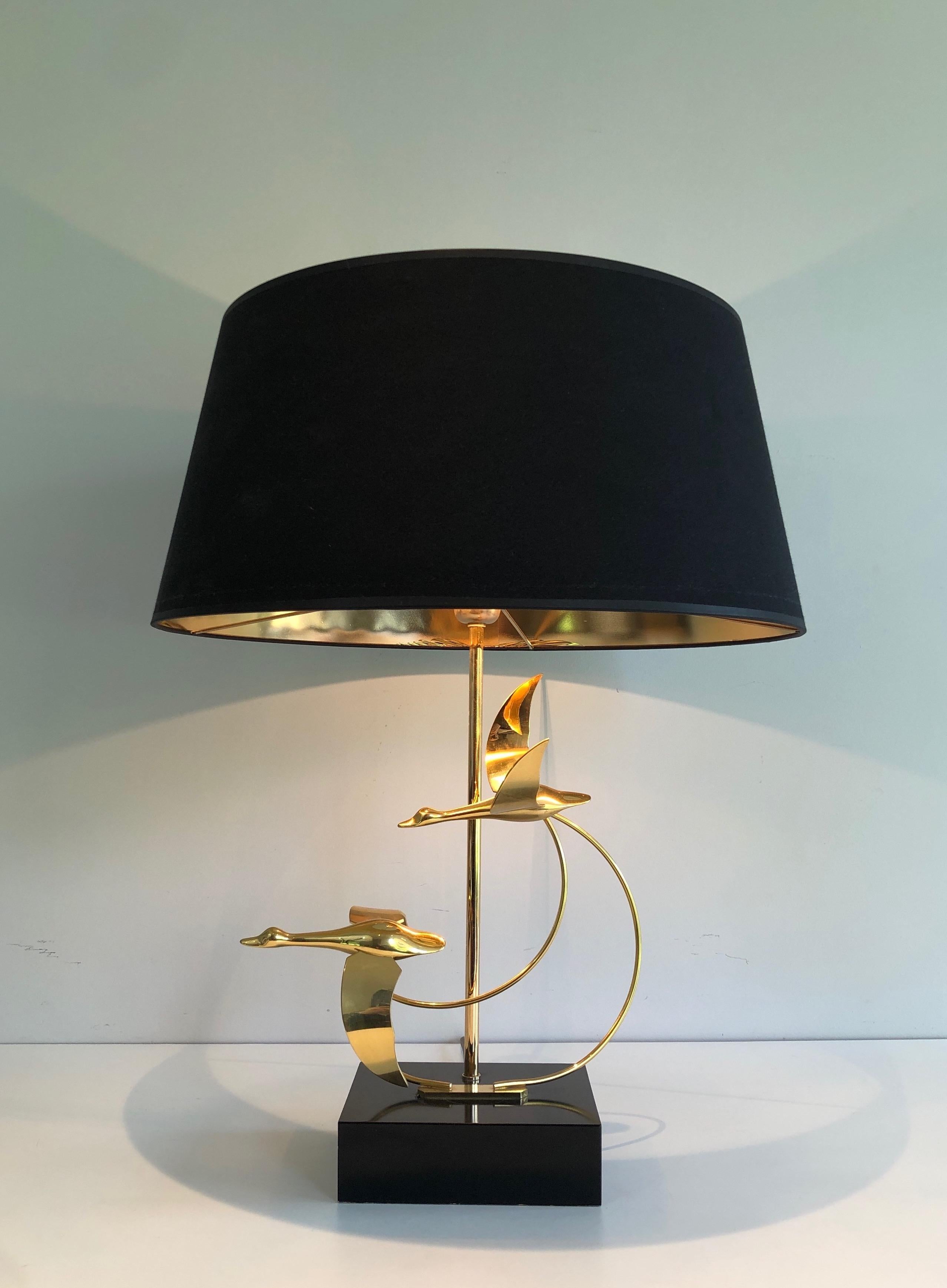 This table lamp shows a flock of wild geese. This lamp is made of brass on a black lacquered wooden base. This is a French work, circa 1970.