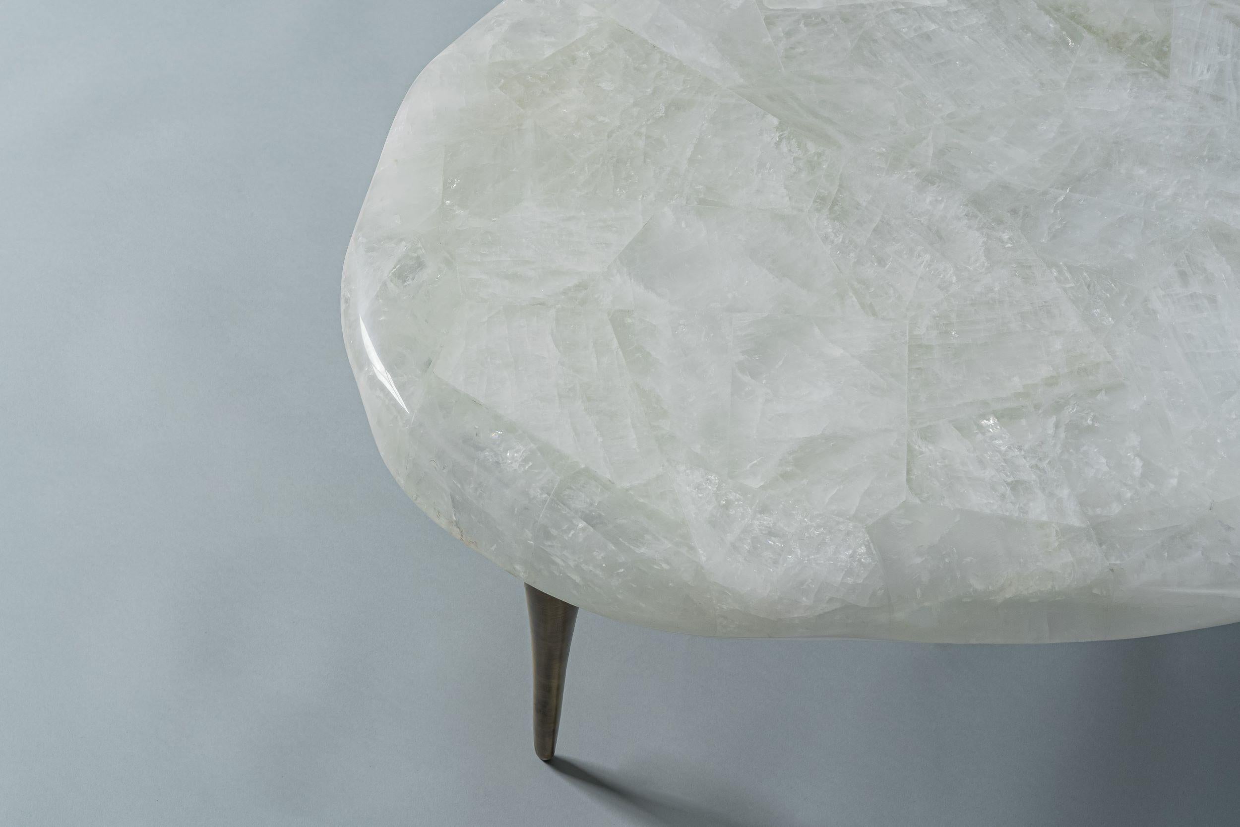 La Collection S'inspire de la Nature, avec des bords ondulés et des pieds effilés qui rappellent la fonte des glaces. Les plateaux profilés en quartz cristallin reposent délicatement sur des pieds en bronze coulés à la main, conférant au design une