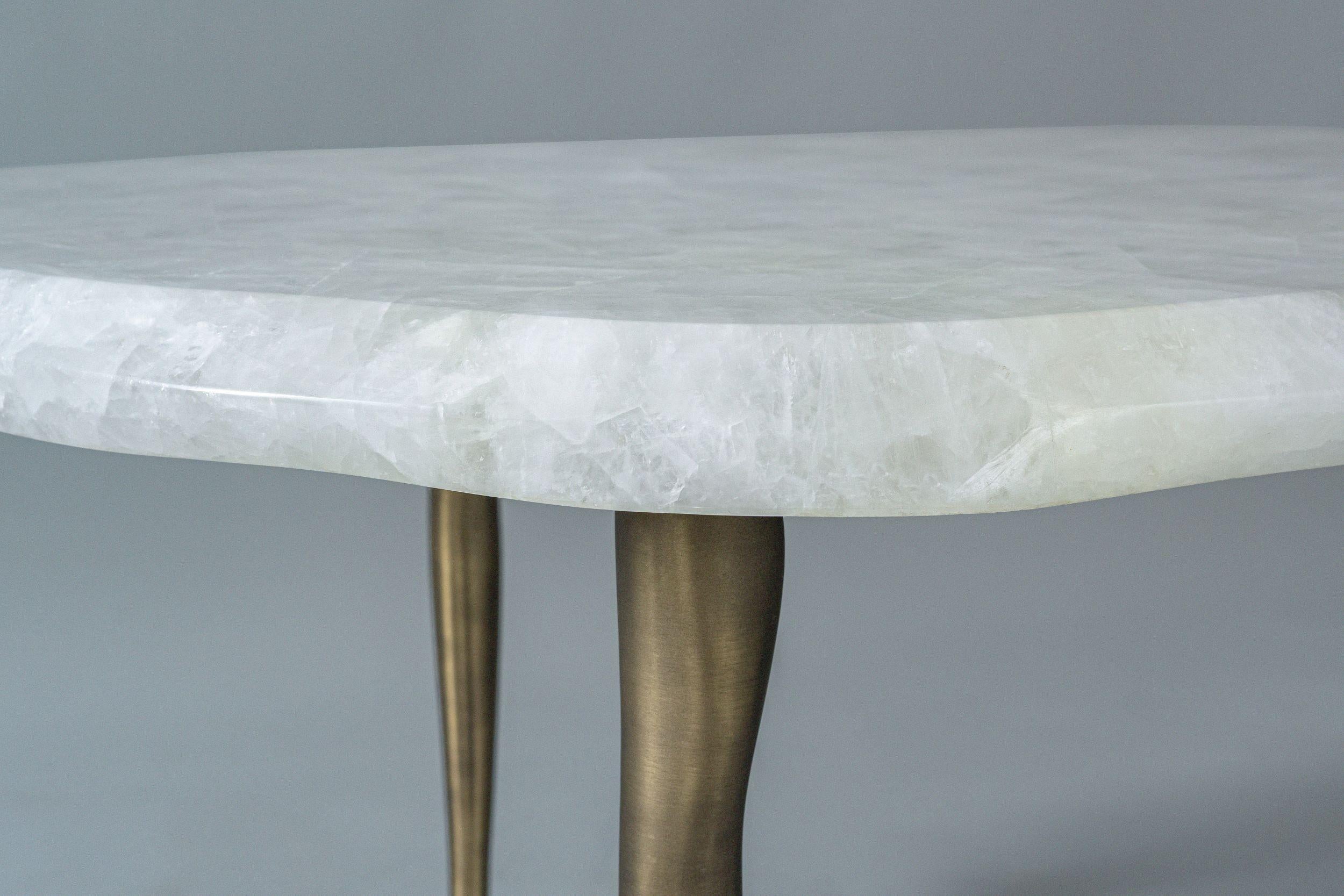 La Collection S'inspire de la Nature, avec des bords ondulés et des pieds effilés qui rappellent la fonte des glaces. Les plateaux profilés en quartz cristallin reposent délicatement sur des pieds en bronze coulés à la main, conférant au design une