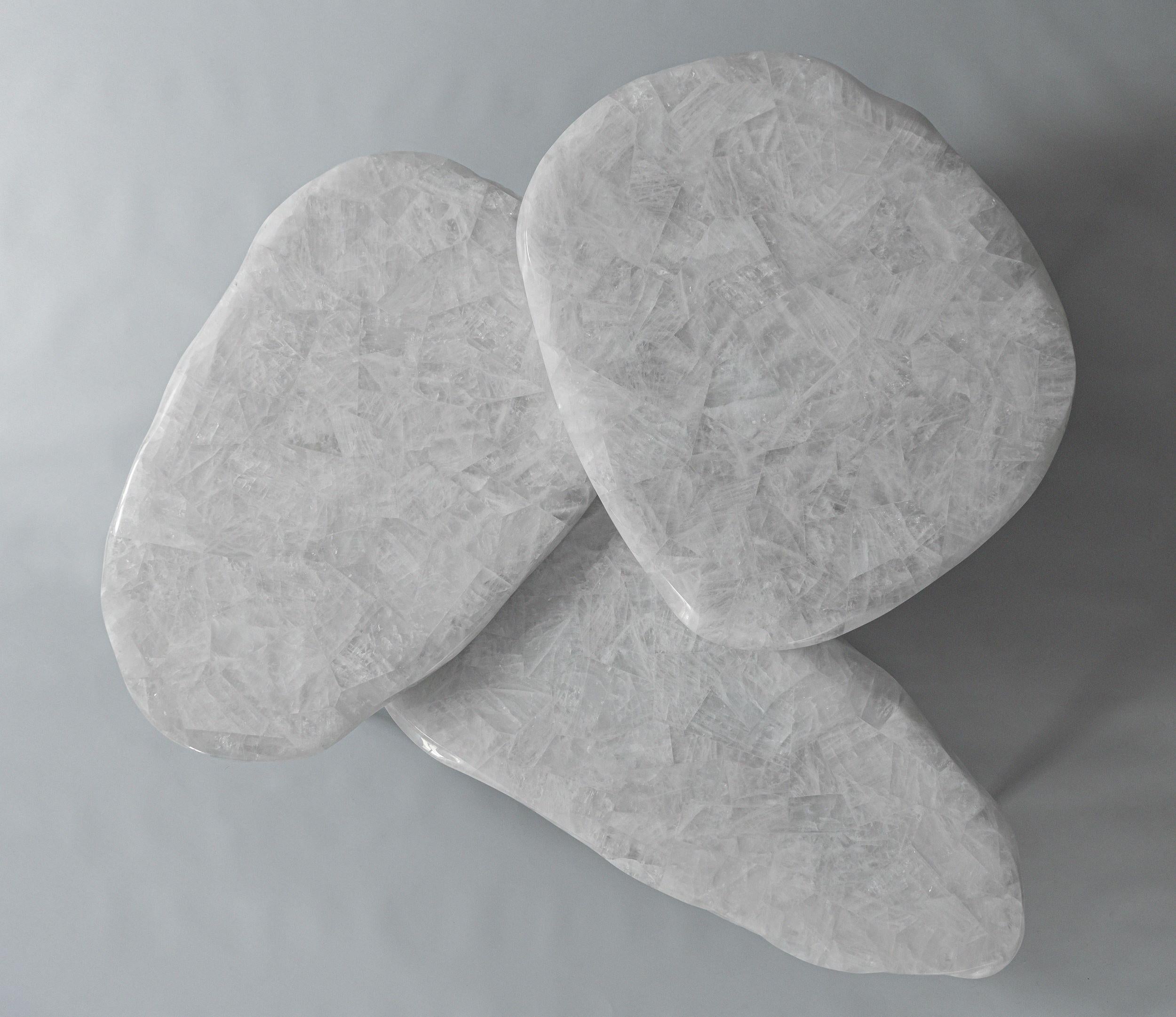 La Collection S'inspire de la Nature, avec des bords ondulés et des pieds effilés qui rappellent la fonte des glaces. Les plateaux profilés en quartz cristallin reposent délicatement sur des pieds en bronze coulés à la main, conférant au design une