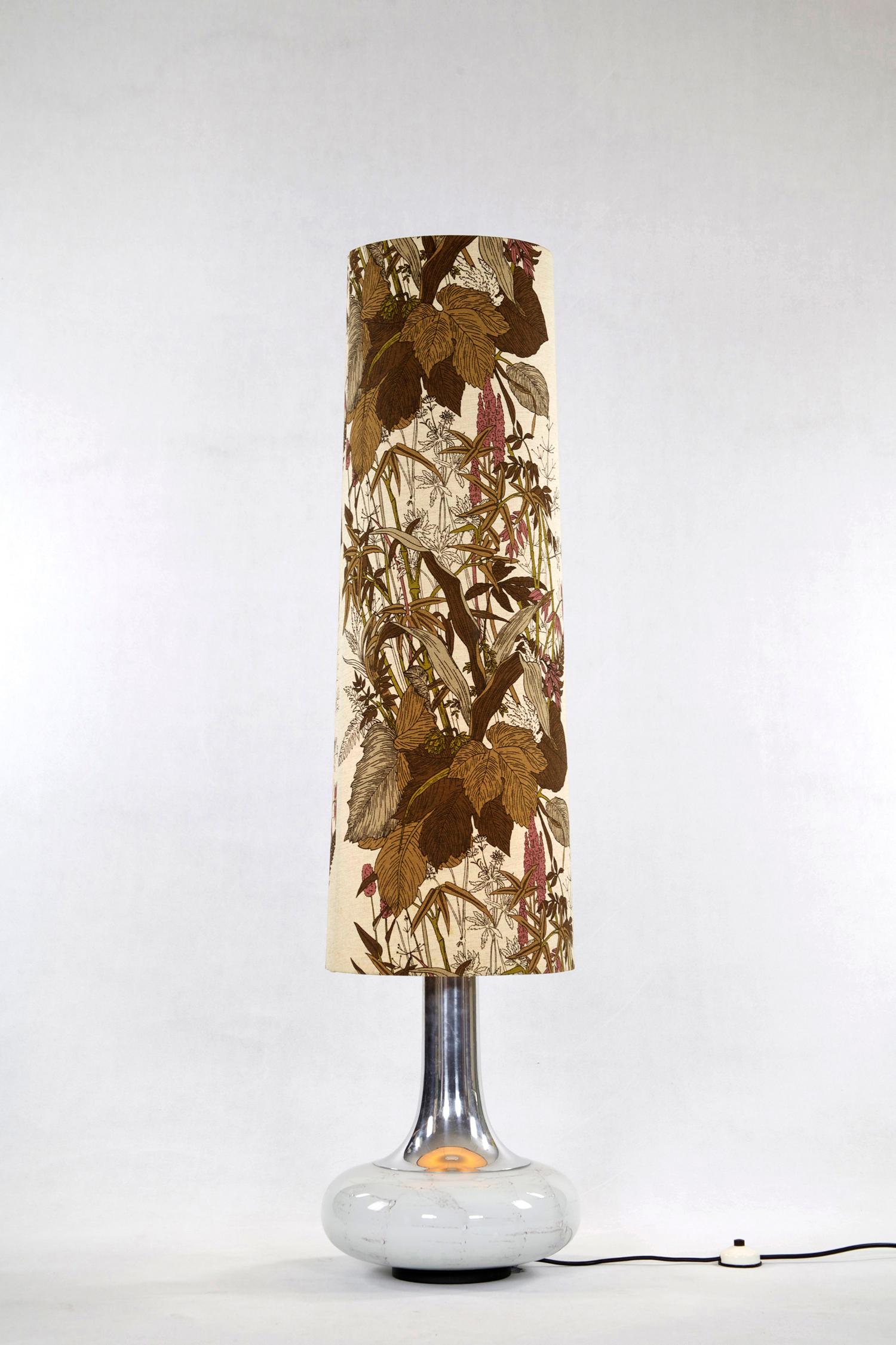 This floor Lamp was designed in the 1970s. It consists of an illuminated glass base and fabric shade with floral pattern.

Feel free to contact us for more detailed pictures.

