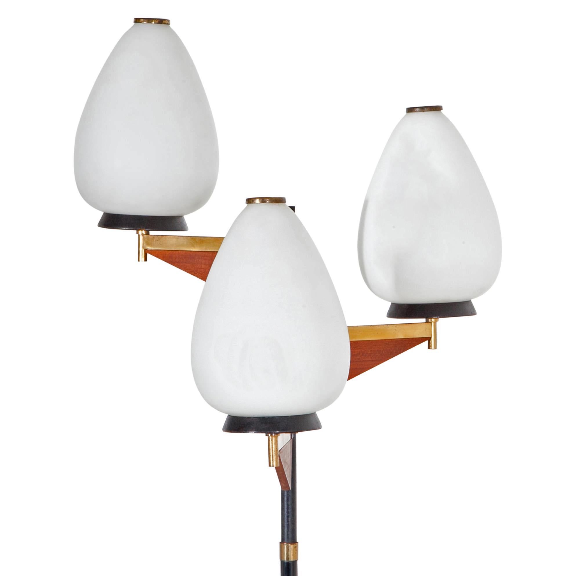 Floor lamp on a round metal foot with a slim metal rod and three conical opaque glass shades, mounted on brass arms with wooden elements. Old Italian wiring. 

For the electrification we assume no liability and no warranty.