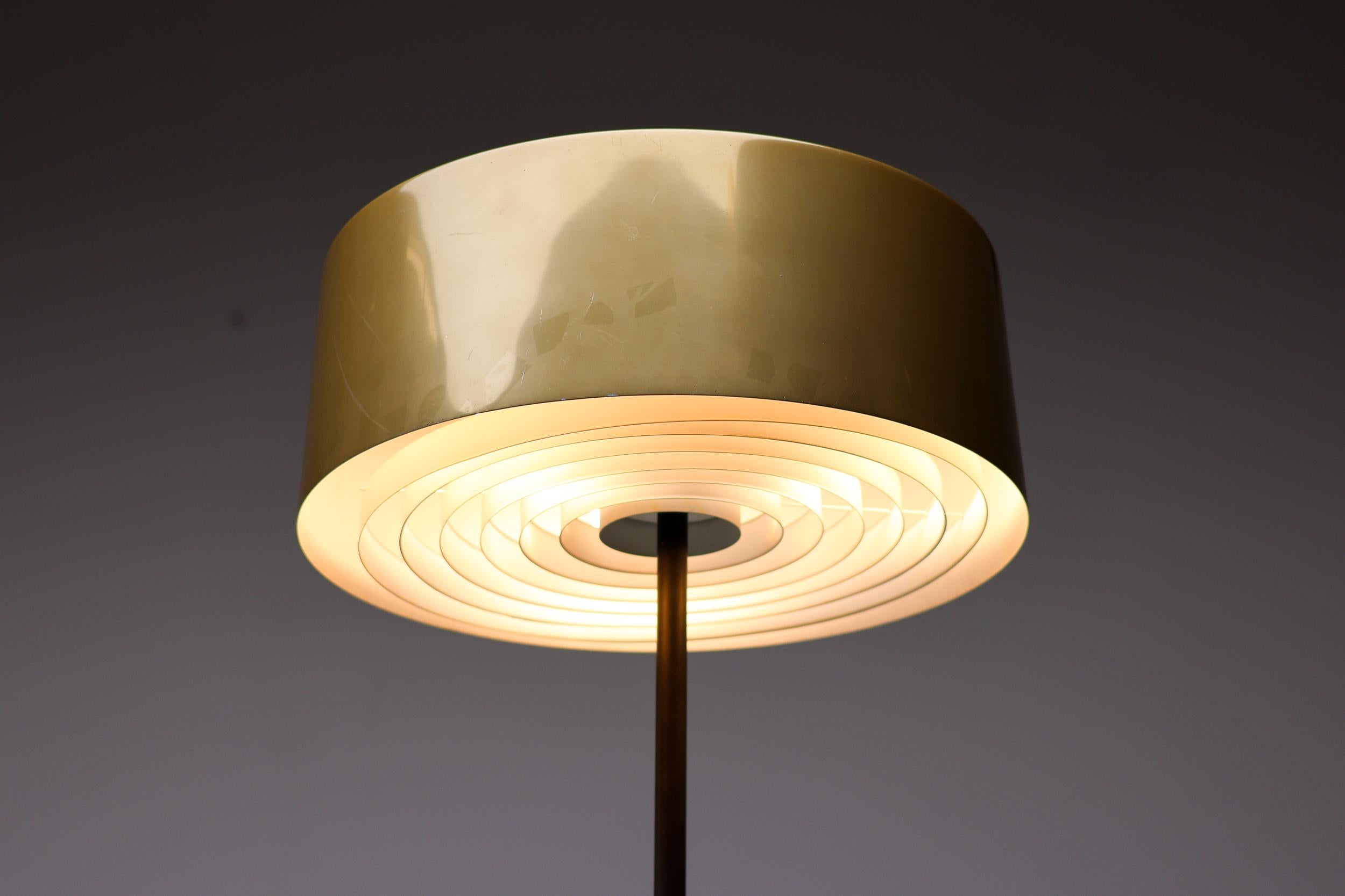 Magnifique lampadaire des années 1950, avec un abat-jour en aluminium émaillé de couleur bronze doux et brillant. 
Conçu par Lisa-Johansson Pape et fabriqué par Orno. 
La partie supérieure de l'abat-jour est recouverte de verre, la partie inférieure