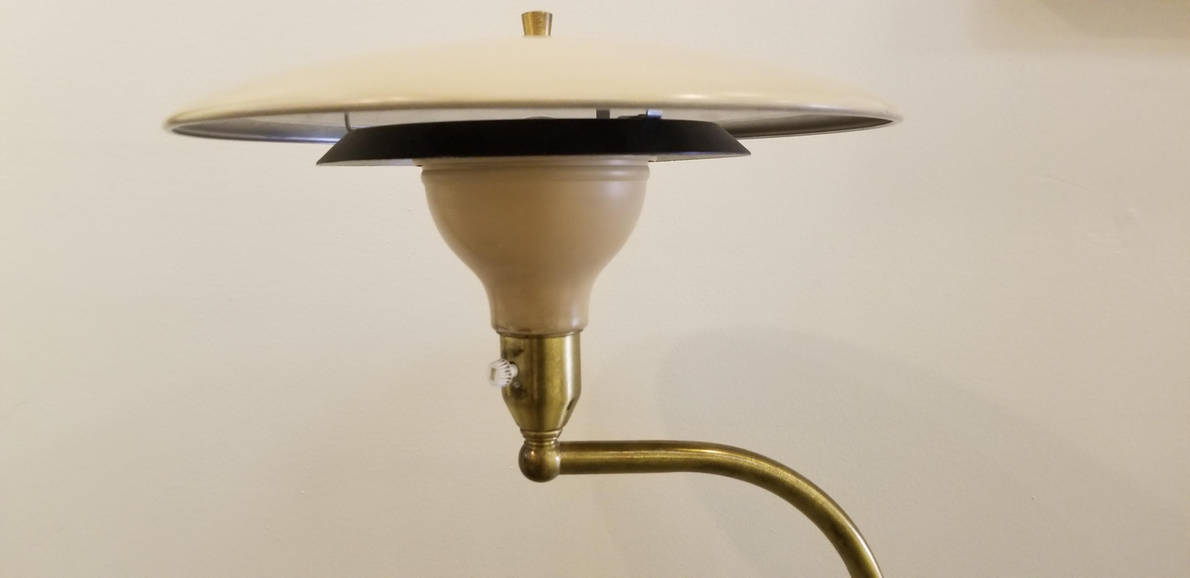 A Mid-Century Modern adjustable floor lamp by M. G. Wheeler Co., circa 1960s. Flying saucer design to metal shade. Lamp pivots and height adjusts. Original condition with original painted aluminum and metal. Retains makers label.