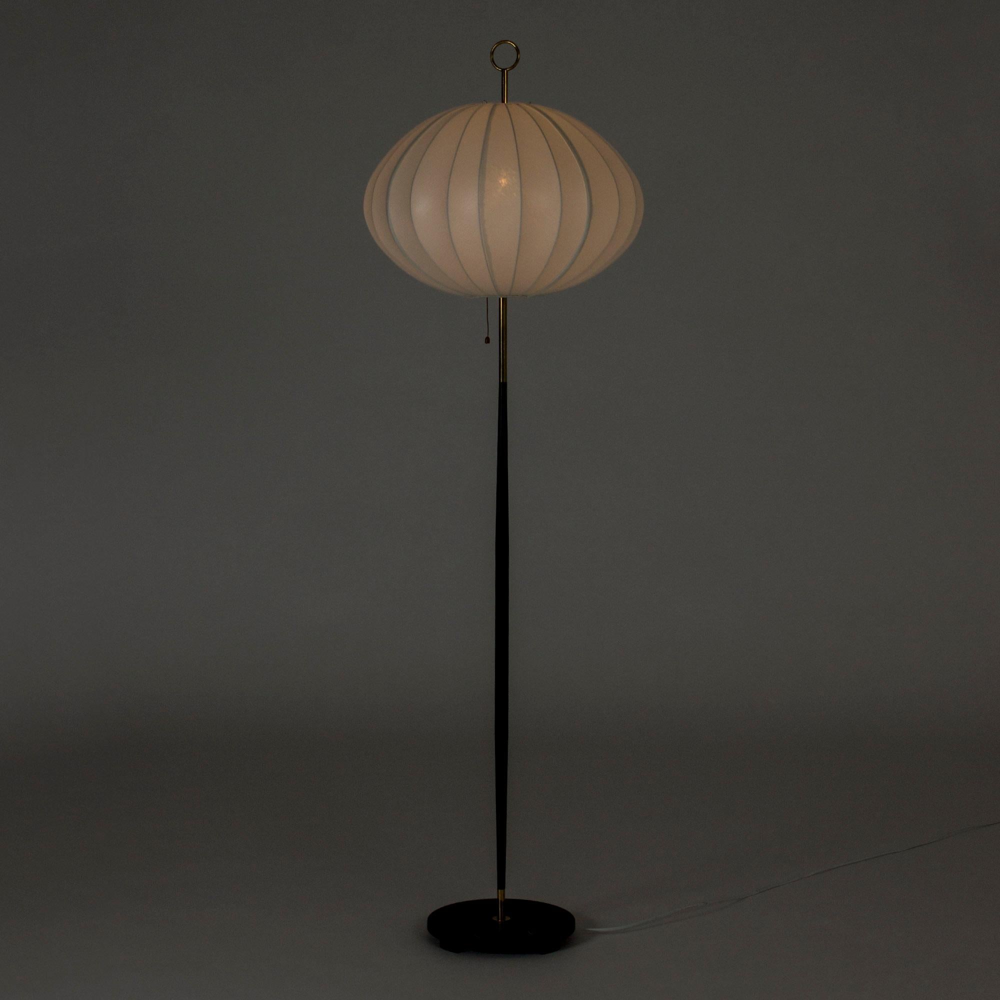 Amazing floor lamp by Svend Aage Holm Sørensen, with a black lacquered metal base. Large, oval lamp shade that spreads a beautiful light, decorative brass ring at the top. Great contrast between the wide shade and the slender base.