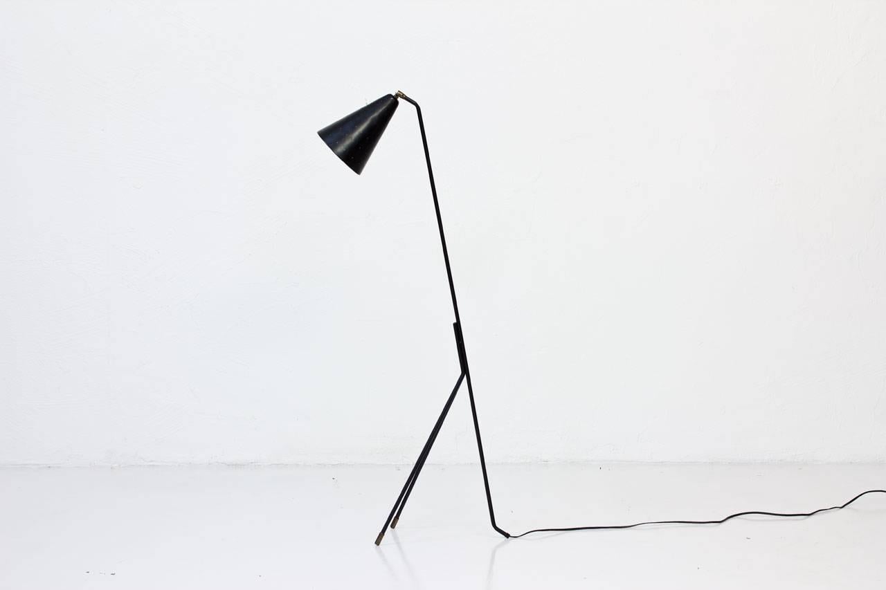 Rare floor lamp designed by Svend Aage Holm Sørensen. Produced by his own company Holm Sørensen & Co, Denmark during the 1950s. Lamp in black lacquered metal with adjustable shade featuring a die cut dot pattern. White inside. Brass feet
and joint.