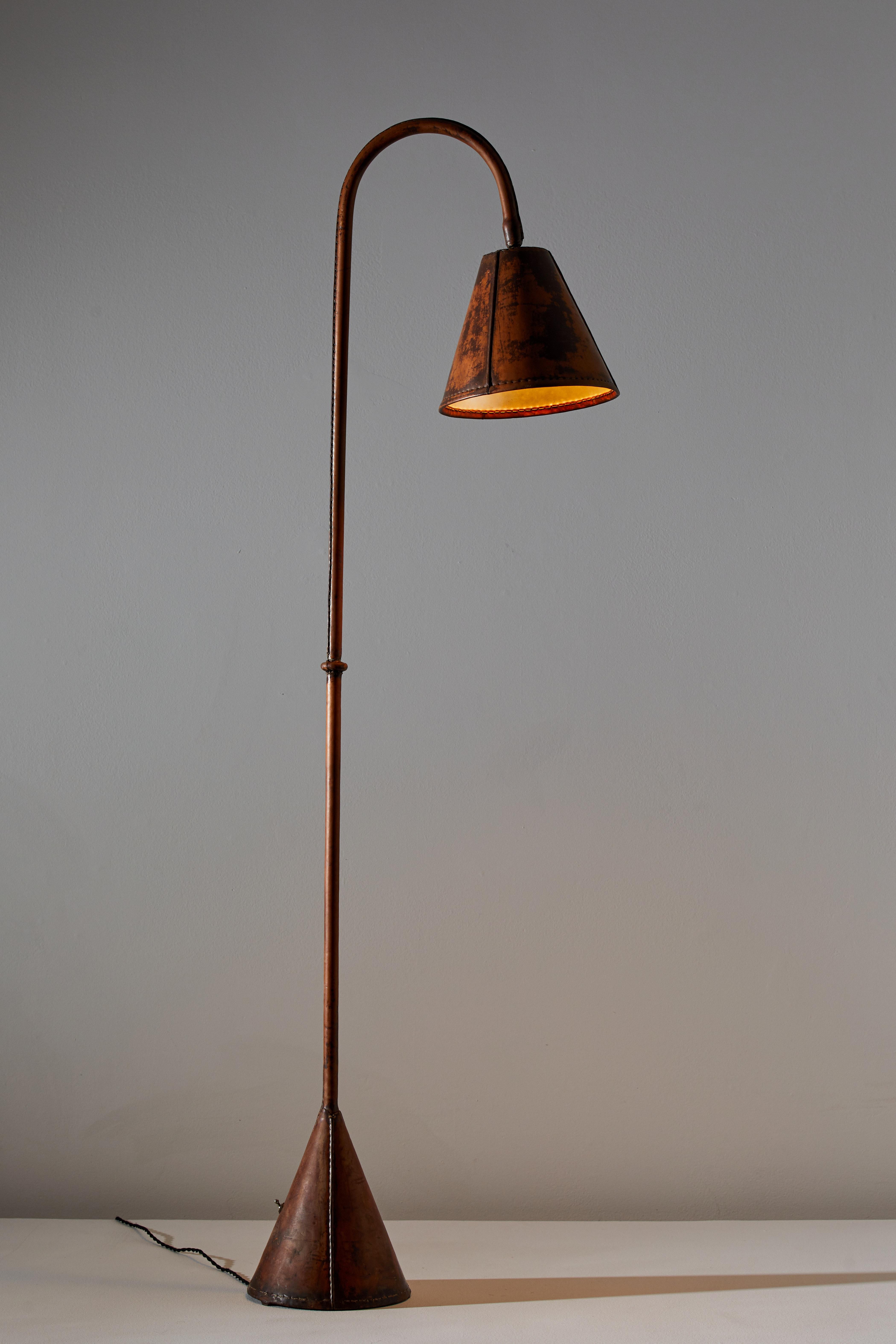 Floor lamp by Valenti. Manufactured in Spain, circa 1950s. Saddle-stitched distressed leather over steel. Shade articulates up/down and left/right. On/off switch on base of lamp. Rewired for U.S. sockets with black French twist cord. Takes one E27