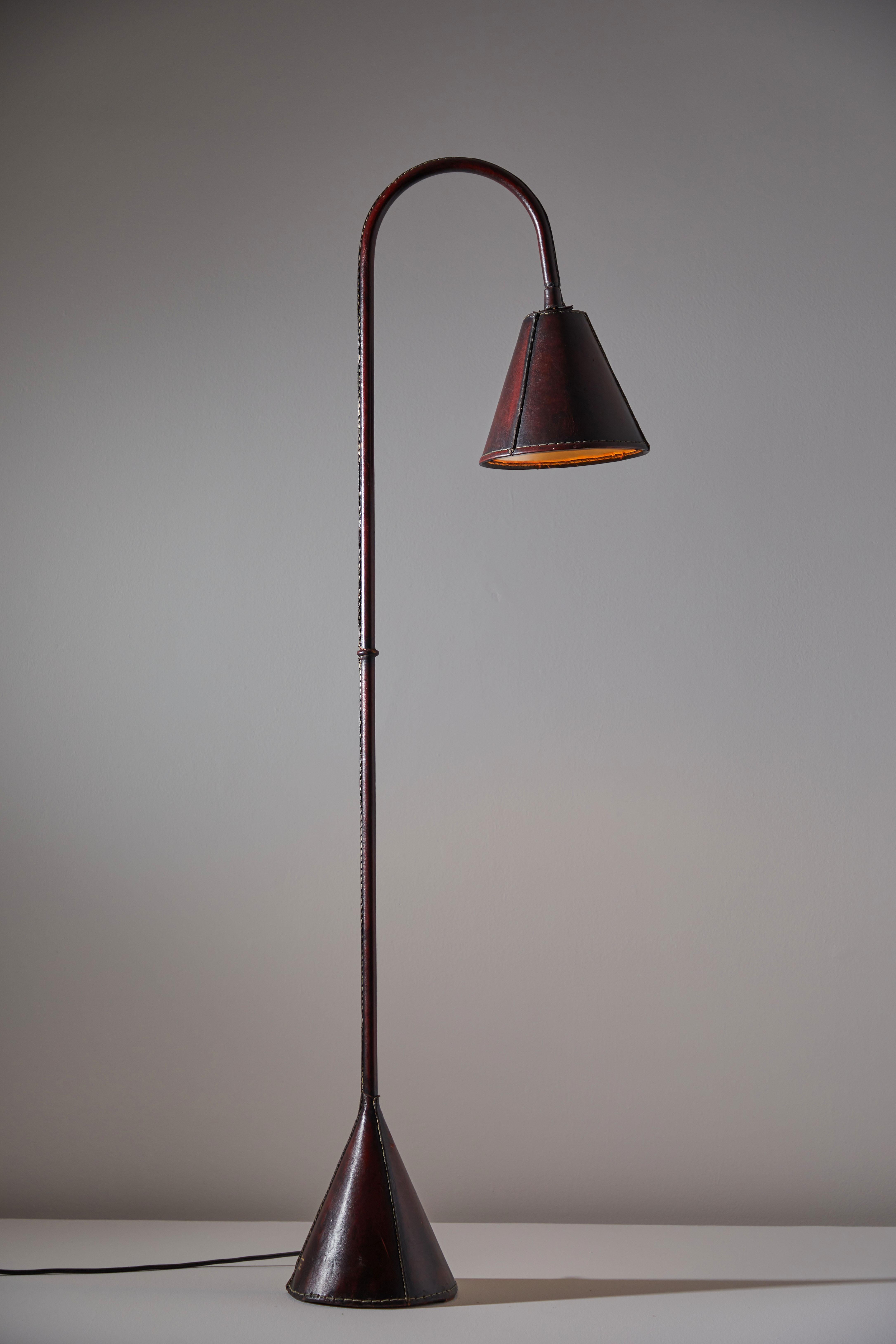 Floor lamp by Valenti. Manufactured in Spain, circa 1960s. Saddle-stitched distressed leather over steel. Shade articulates up/down and left/right. On/off switch on base of lamp. Rewired for U.S. sockets with black French twist cord. We recommend