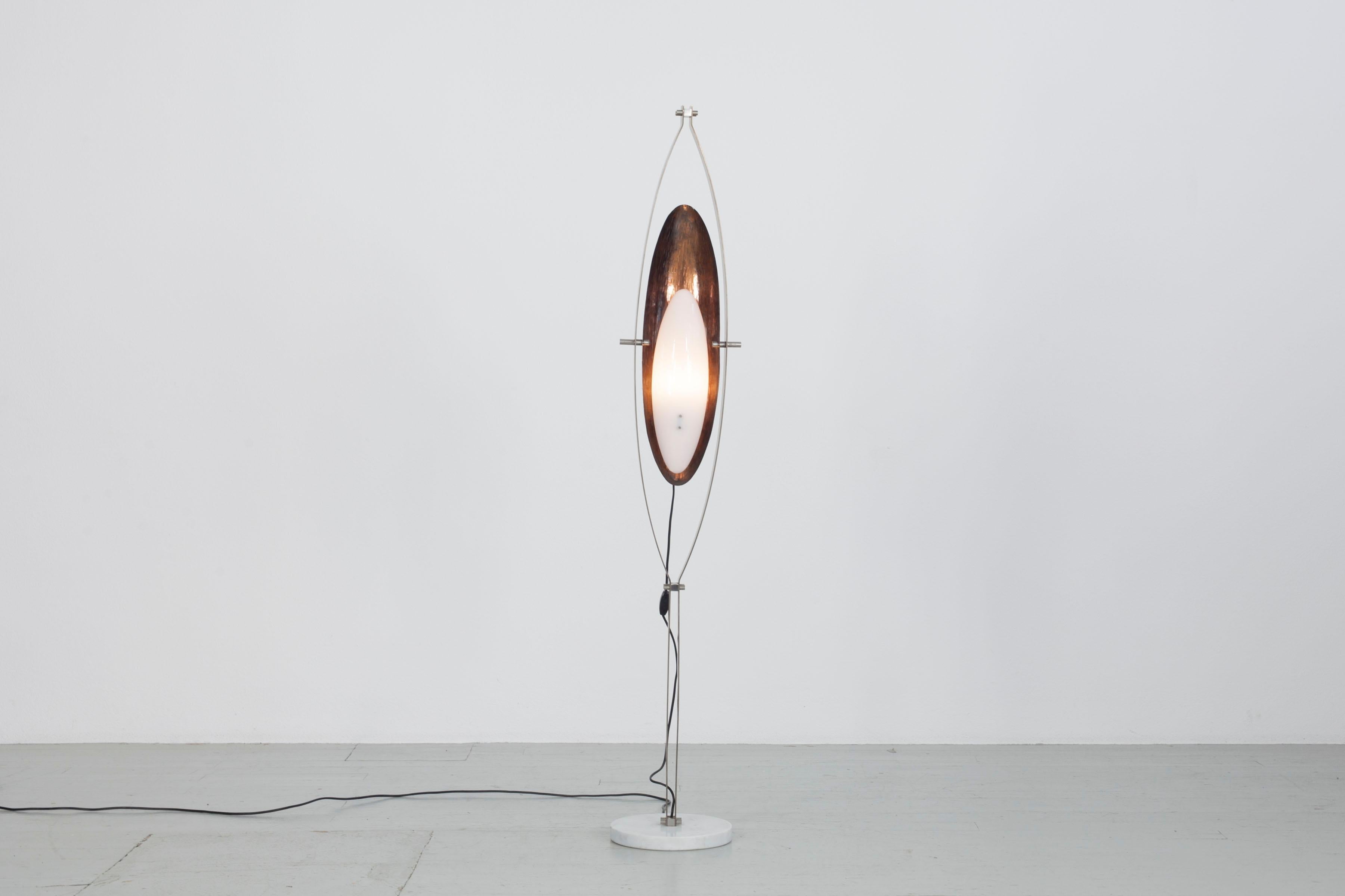 Sculptural floor lamp by Goffredo Reggiani circa 1960. Crafted from satin steel, copper, and white plexiglass, atop a marble base. Features European plug compatibility.

The lamp comprises a marble foot, matted chrome frame, hammered copper back