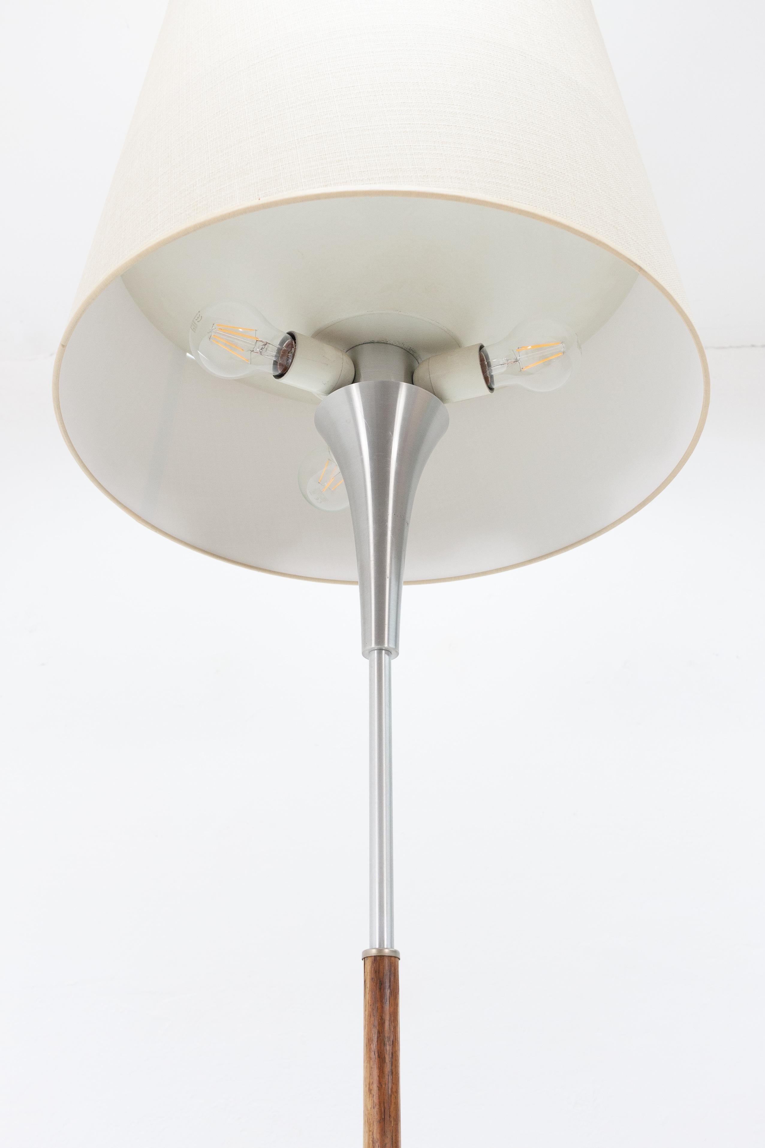 Superb floor lamp. Dijkstra, Holland, 1970s, aluminium base with new fabric hood. The lighting is divided into two sections, an upper half which spreads light upwards using a reflector dividing the hood horizontally and three downwards-facing
