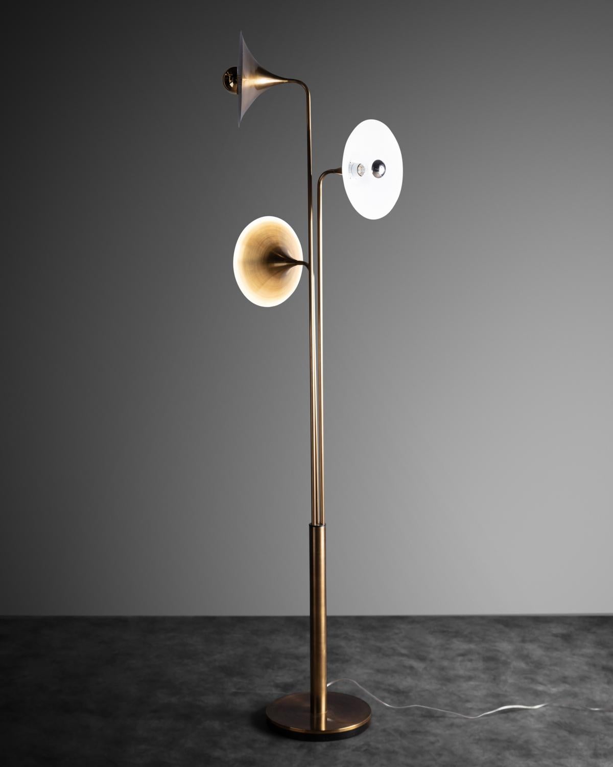 Lampe aus gedrehtem Messing mit zentralem Schaft, der drei verstellbare trompetenförmige Lampenschirme trägt.