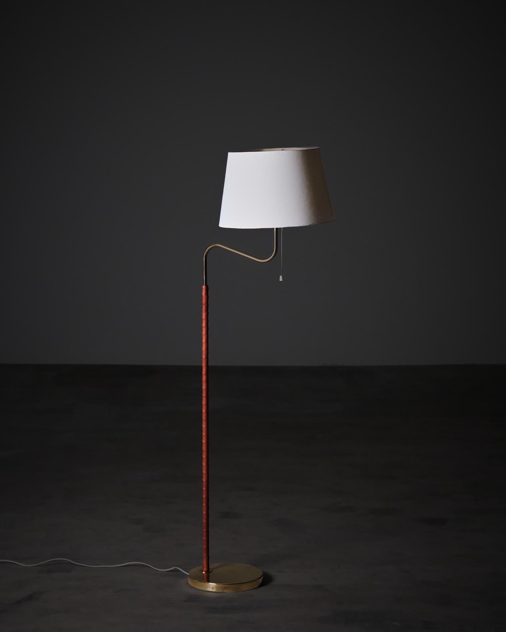 An elegant floor lamp model GX145 by Bergboms, Sweden, 1970s.

The lamp features a brass structure with the stem wrapped in cognac-colored leather, creating a refined contrast between the warm tones of the leather and the polished brass base. The