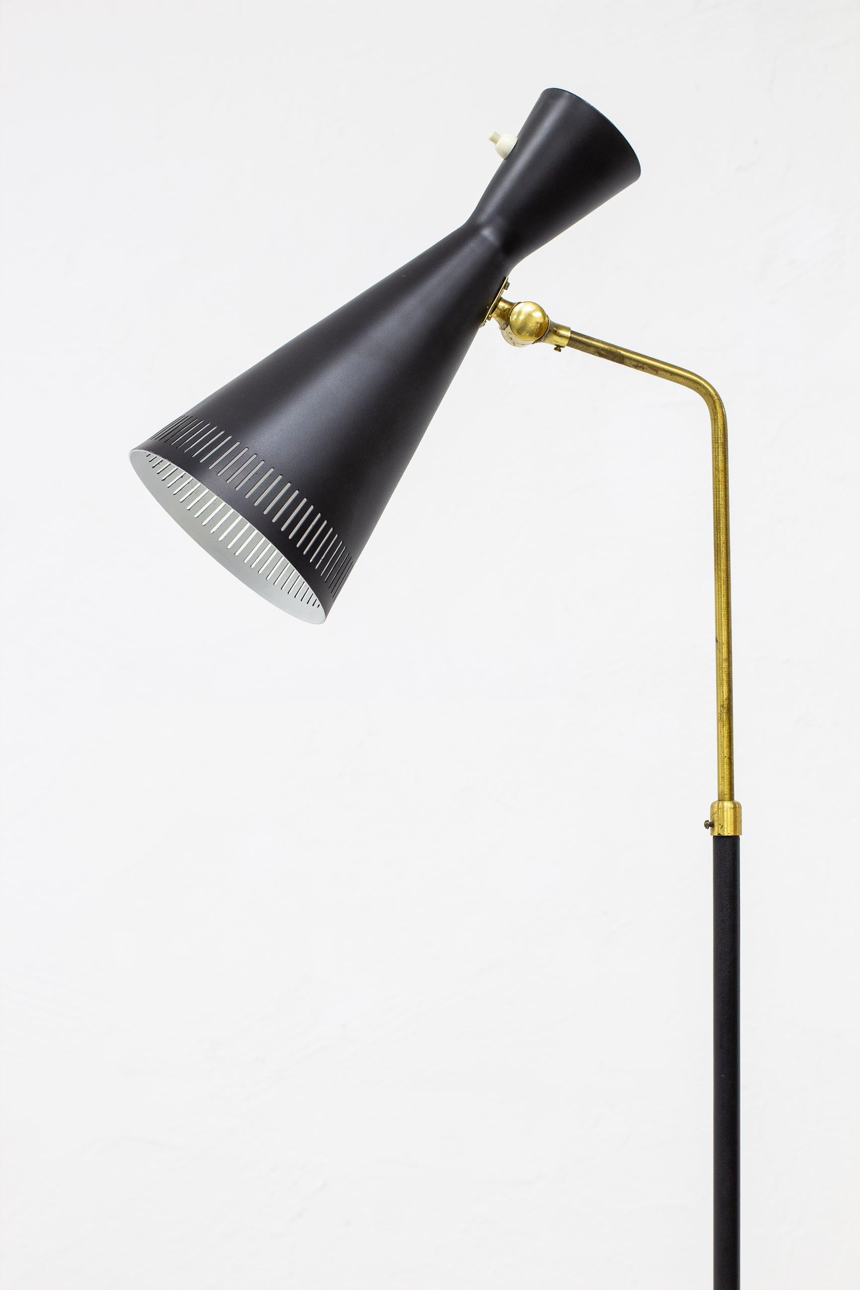 Floor lamp designed and produced in Sweden by Pagos during the 1950s. Made from black lacquered metal and brass. Shade with elegant perforation and Adjustable joint. Light switch on the lamp shade in working order. Very good vintage condition with