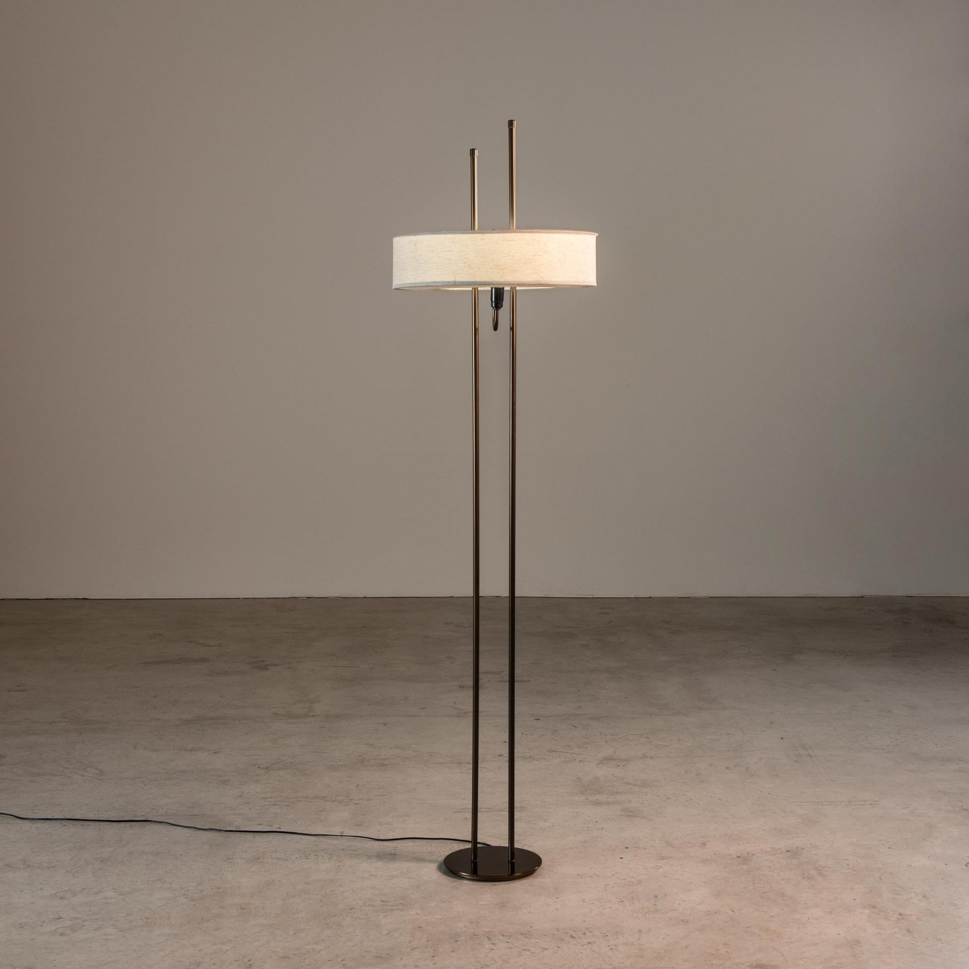 This floor lamp is a paragon of Dominici's design philosophy, which marries the timeless luster of brass with the tactile warmth of linen. The lamp's stature is defined by two parallel brass poles, rising in unison, an embodiment of strength and