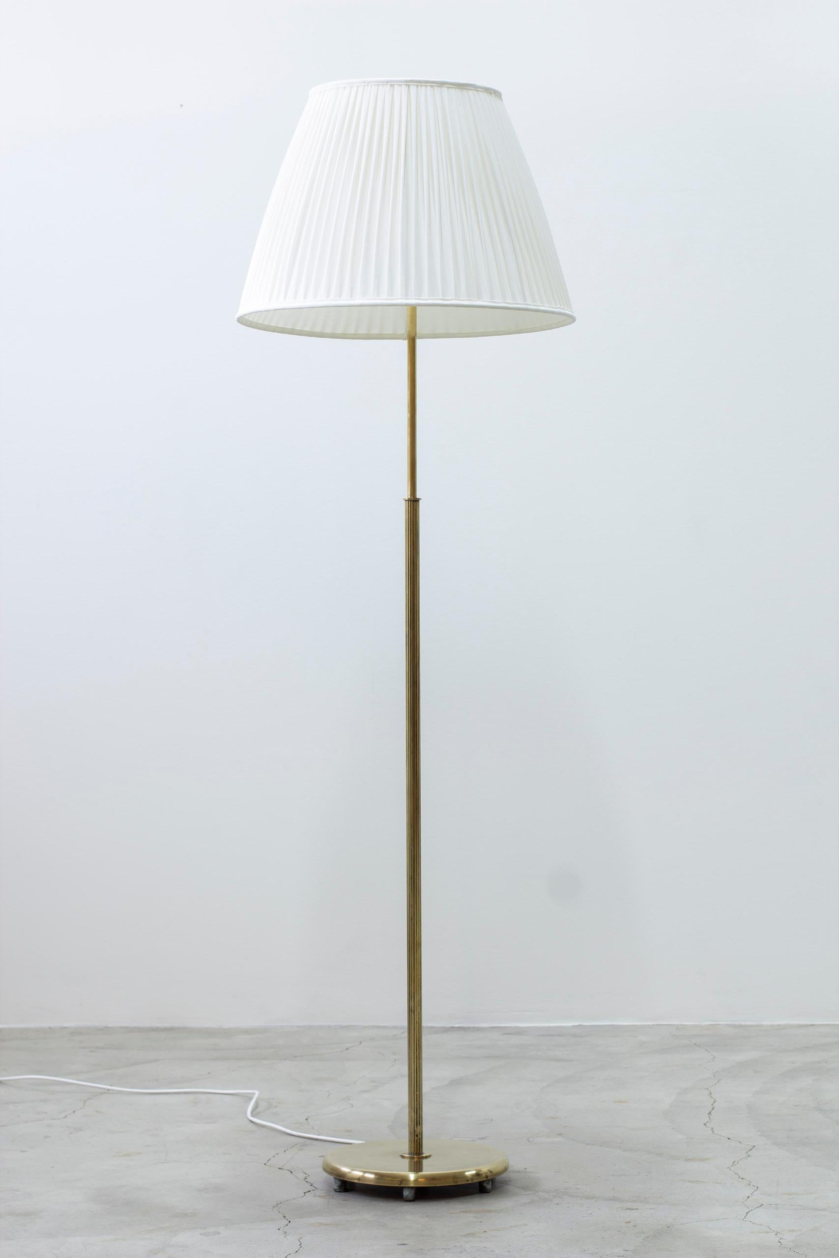 Floor lamp model 15698 designed by Harald Elof Notini. Produced by Arvid Böhlmarks lampfabrik during the 1940s. Polished brass, opaline glass diffuser and lamp shade in chintz cotton. Very good vintage condition with light patina from age and
