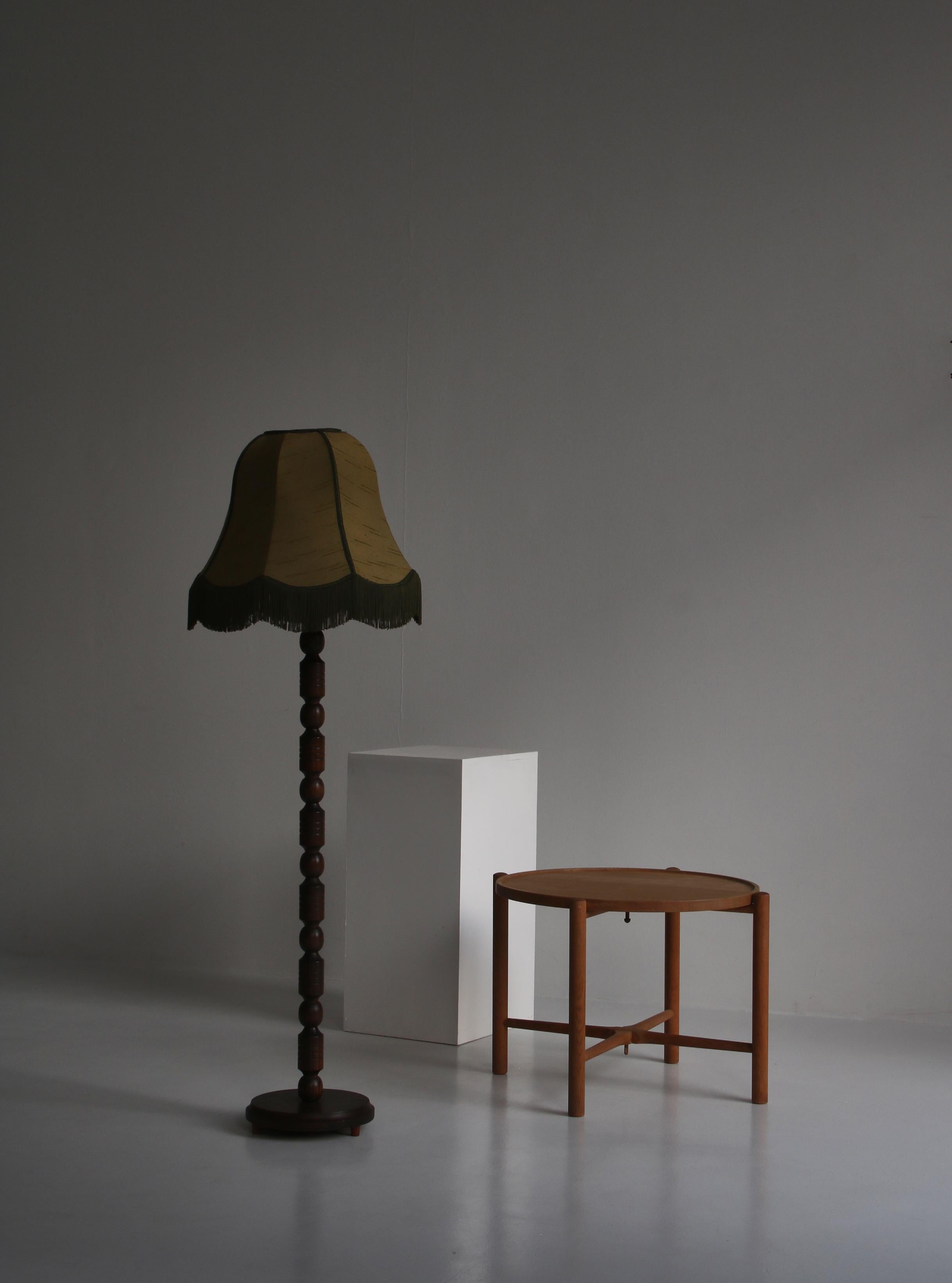 Belle lampe ancienne fabriquée au Danemark dans les années 1930 dans le style Art Déco. La lampe est fabriquée en bois de pin teinté foncé tourné et l'abat-jour est en soie verte avec des franges.