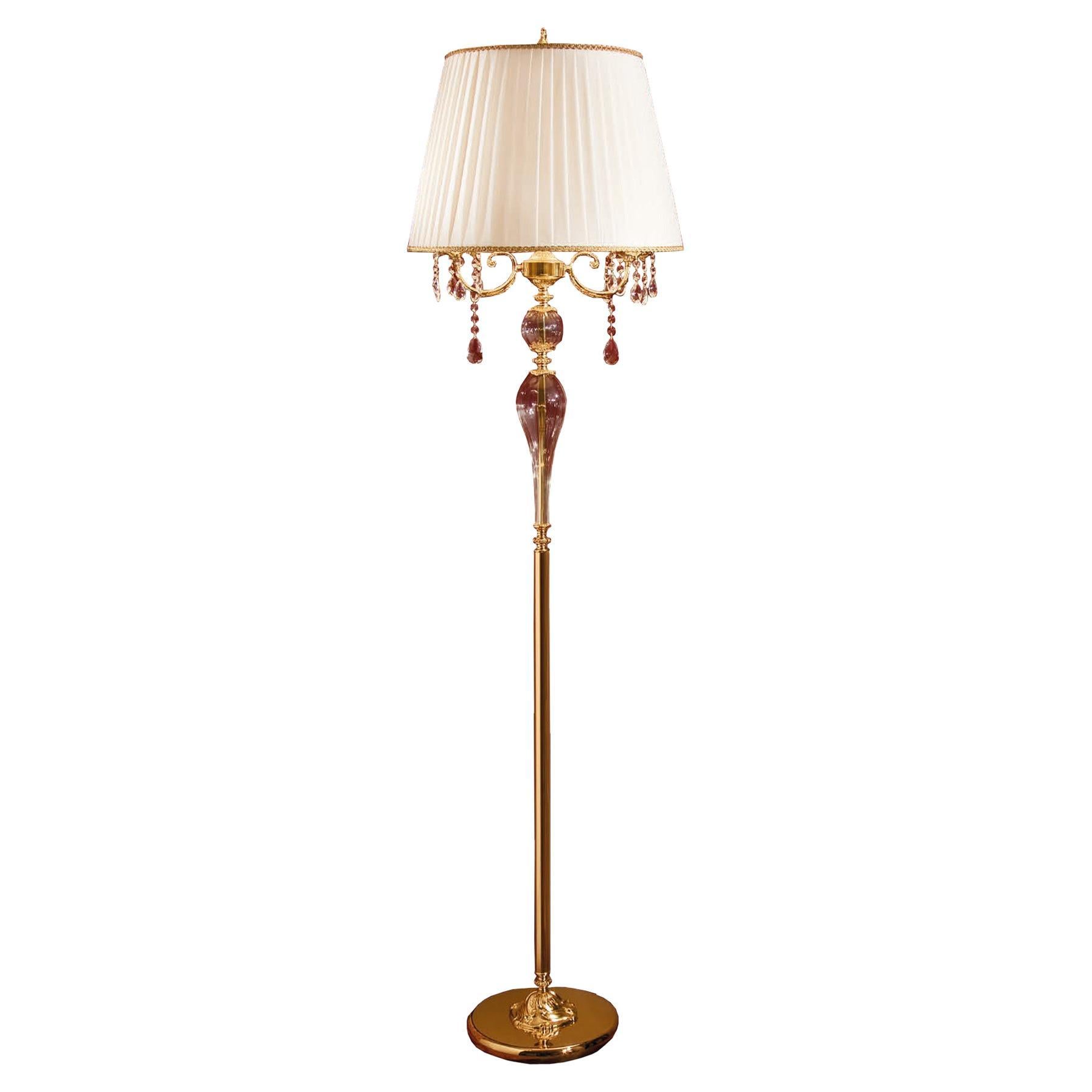 Dive into charme with this Modenese Luxury Interiors floor lamp. The straight line of the central pole, decorated with a 24kt antique gold plated finish, carefully holds 2 lights protected by a wide ivory lampshade, which is decorated at the bottom