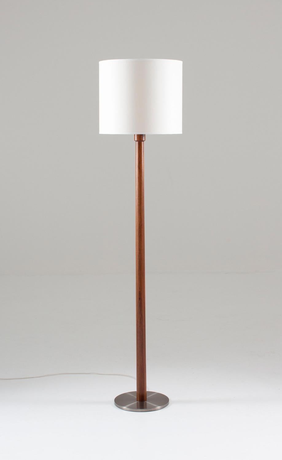 Big floor lamp in rosewood and steel by Uno & Östen Kristiansson for Luxus.
This rare lamp is made of solid rosewood with a foot in brushed steel. The switch is beautifully integrated into the wood. As always with Luxus products, it shows great